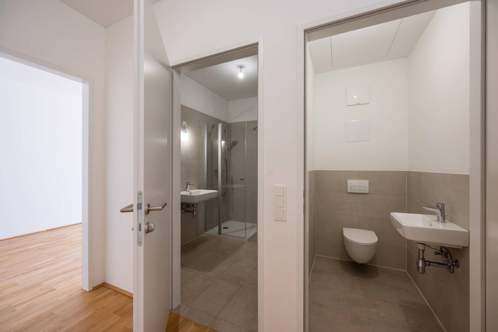 Blick in ein modernes Badezimmer mit Dusche und ein separates Gäste-WC.