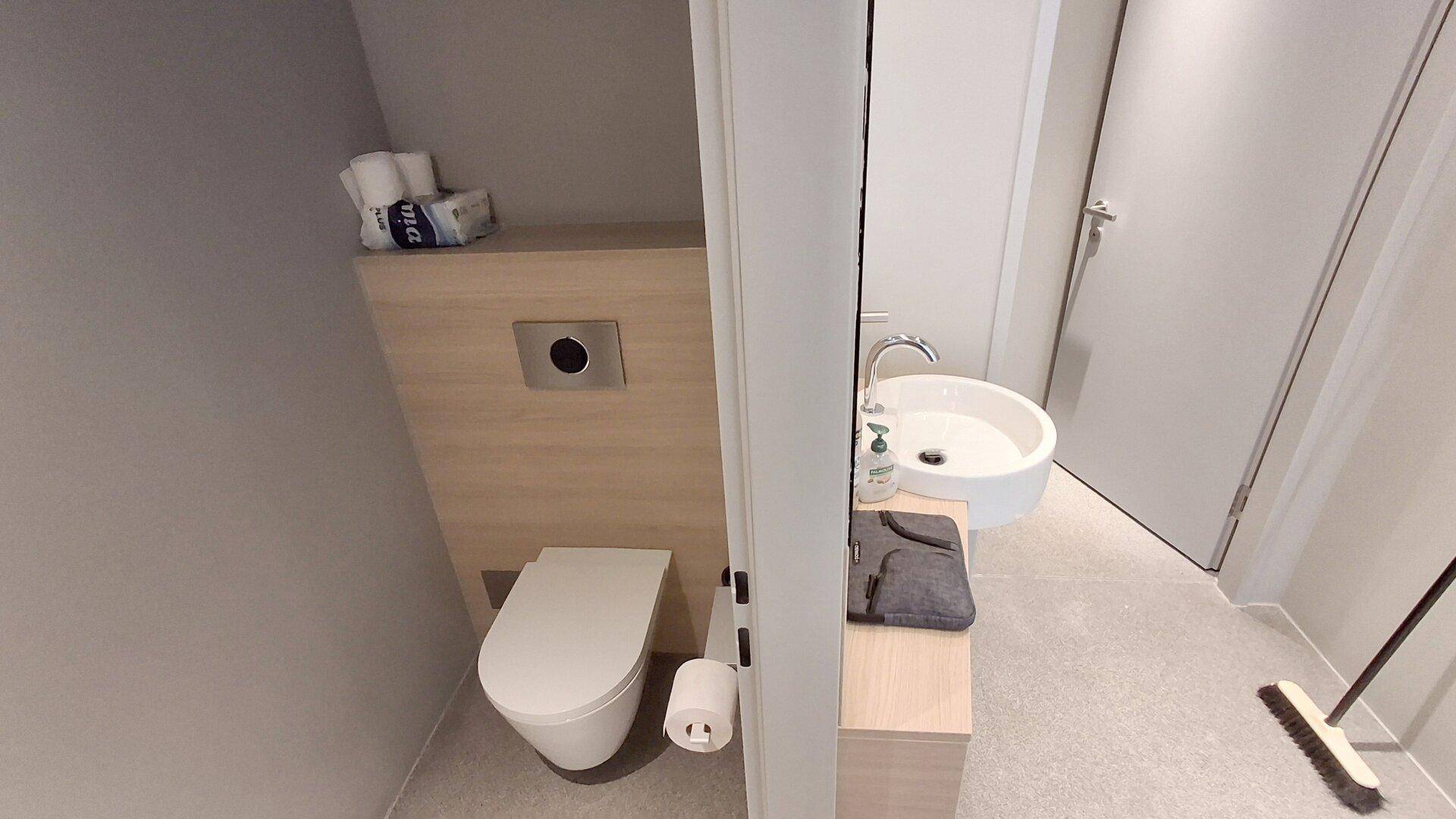 Modernes Gäste-WC mit wandhängender Toilette und stilvoller Holzverkleidung, in gepflegtem Zustand.