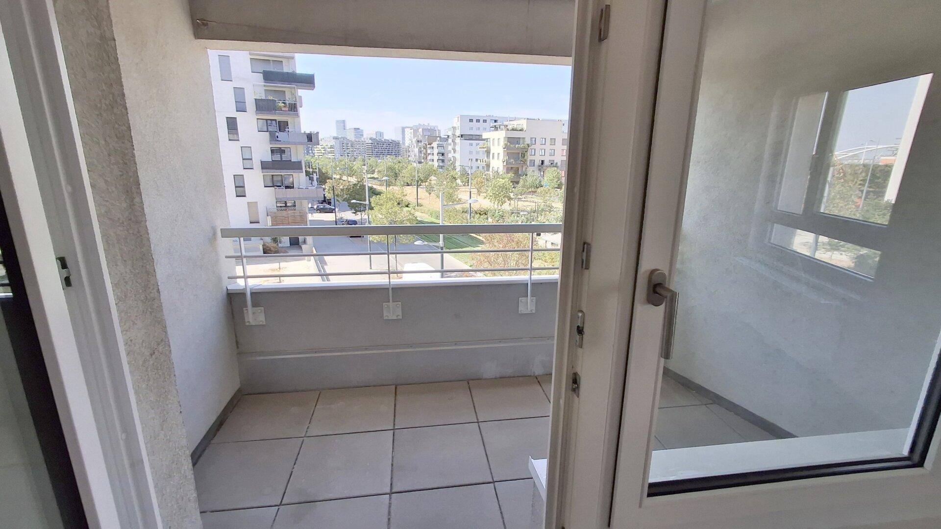 Geräumiger Balkon mit Fliesenboden und Blick auf die umliegenden Gebäude und Grünflächen.