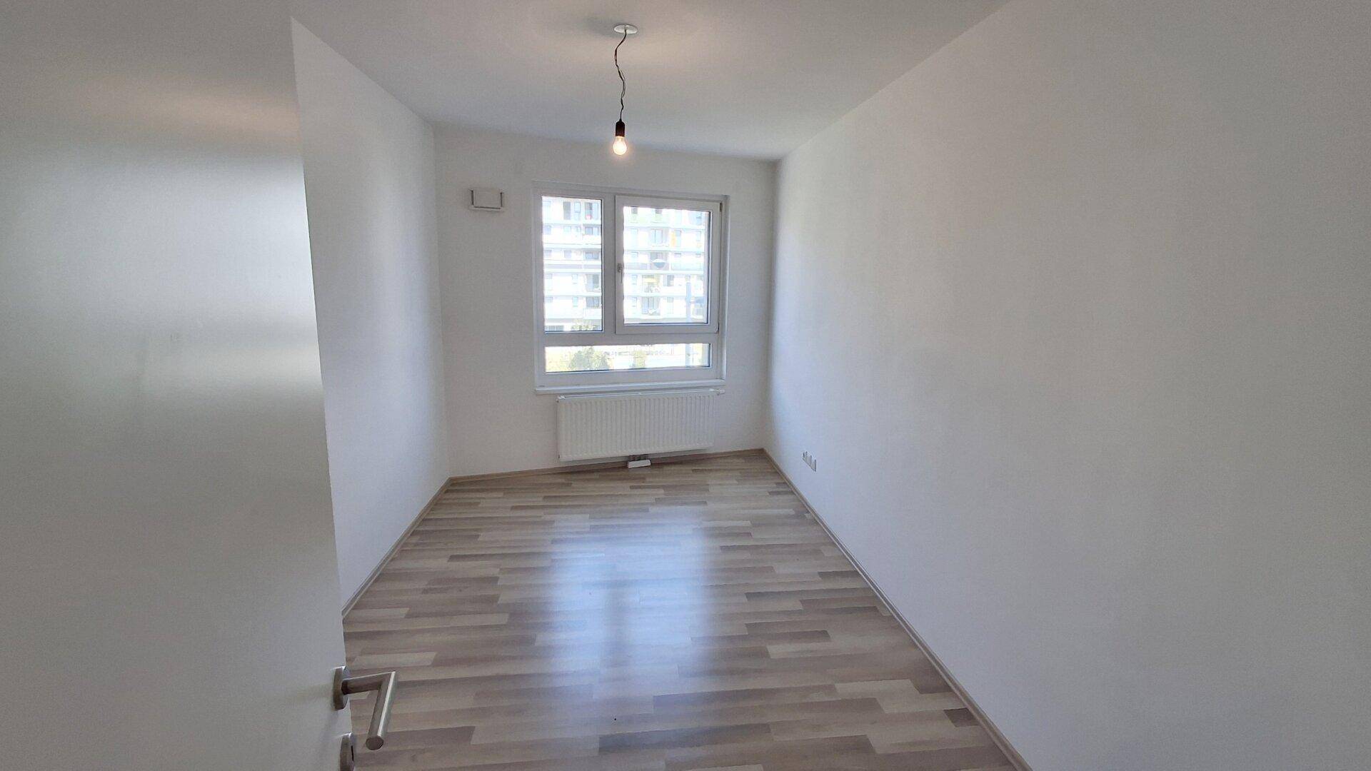 Helles Zimmer mit Laminatboden und großem Fenster, ideal als Schlaf- oder Arbeitszimmer nutzbar.