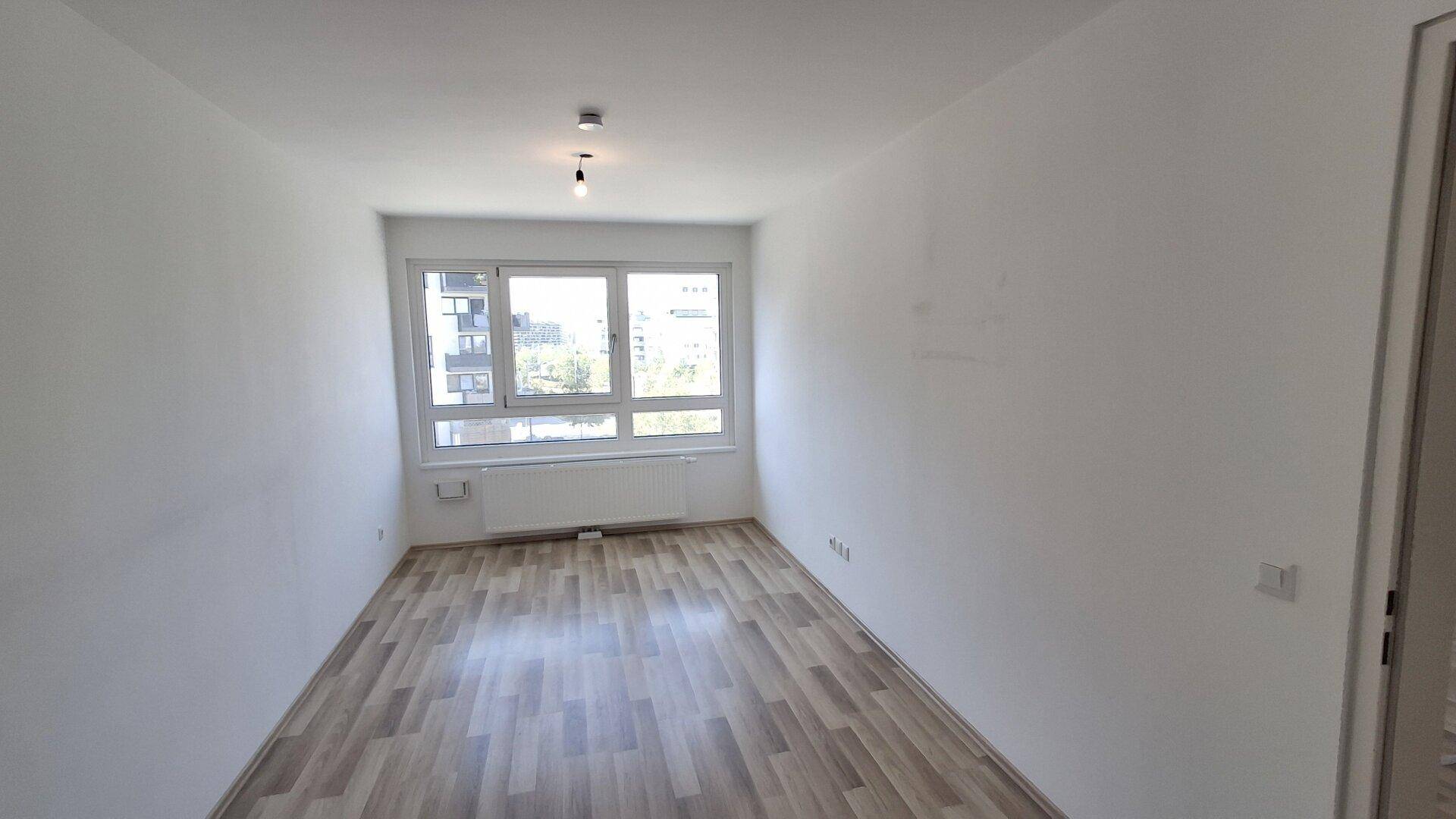 Geräumiges, helles Zimmer mit Laminatboden und großem Fenster, bereit zur individuellen Gestaltung.