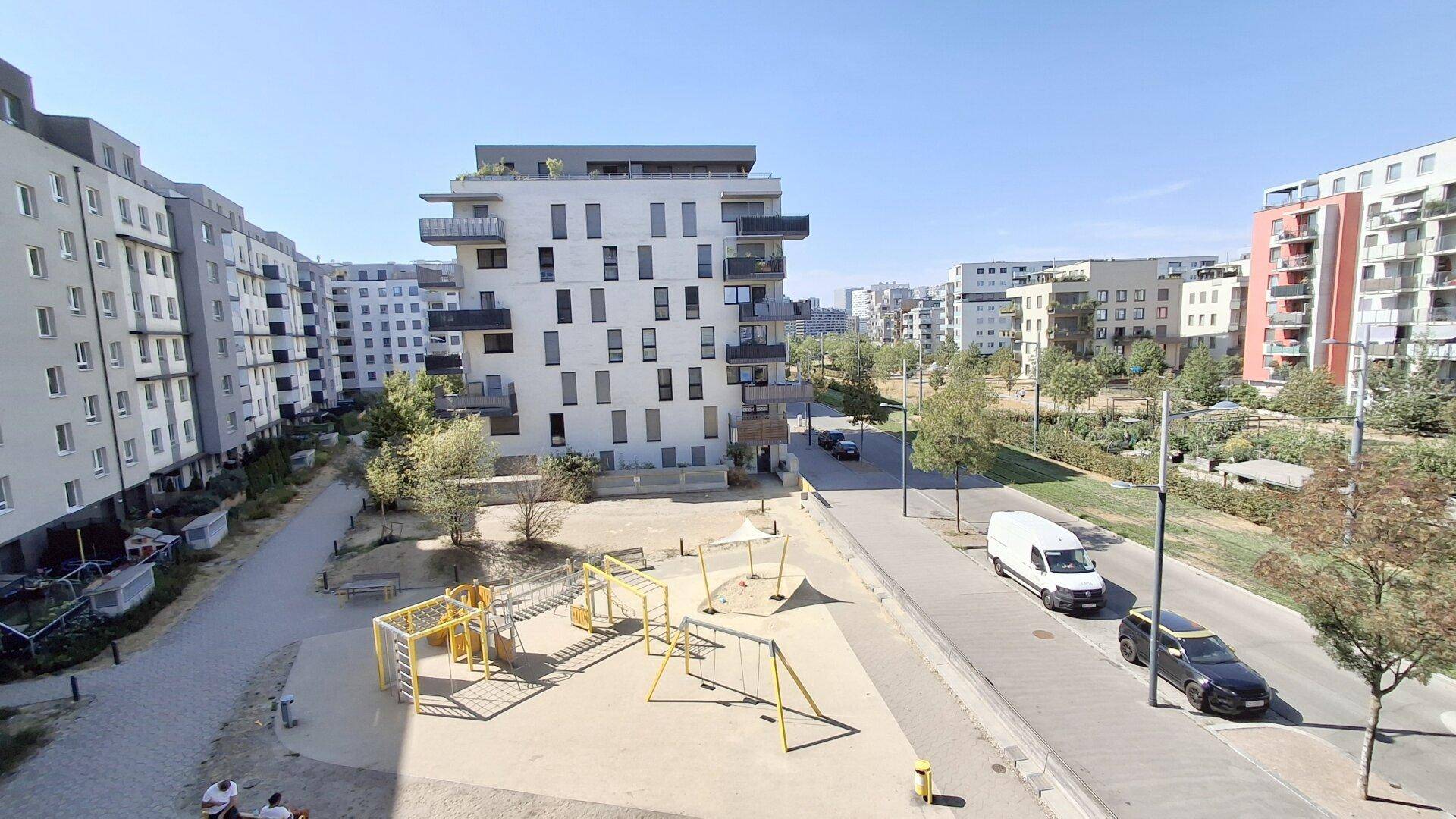 Panoramablick auf einen Spielplatz, die Straße und die umliegenden modernen Wohngebäude der Siedlung.