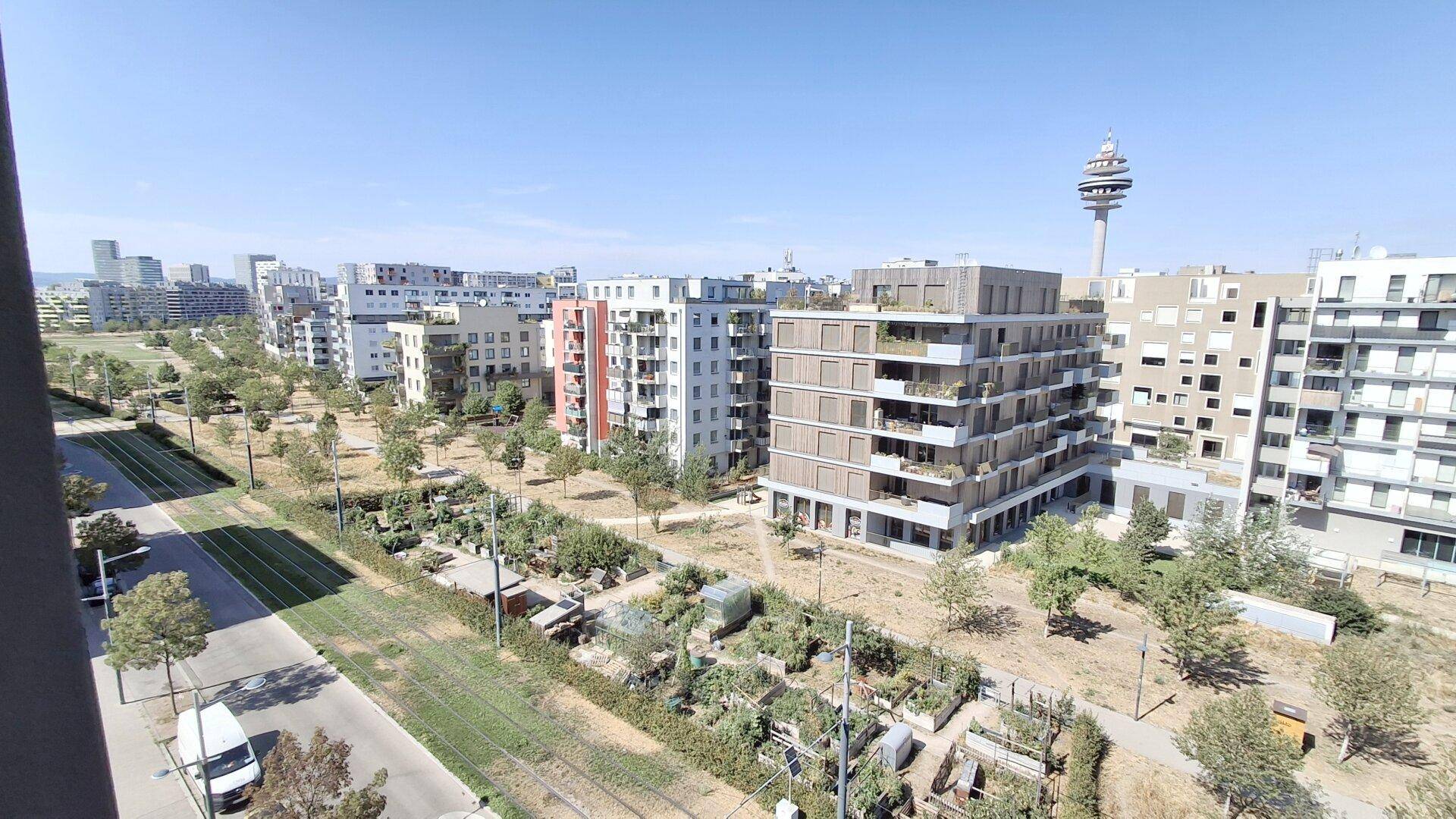 Panoramablick auf eine städtische Umgebung mit Wohngebäuden, Grünflächen und Straßenbahnschienen.