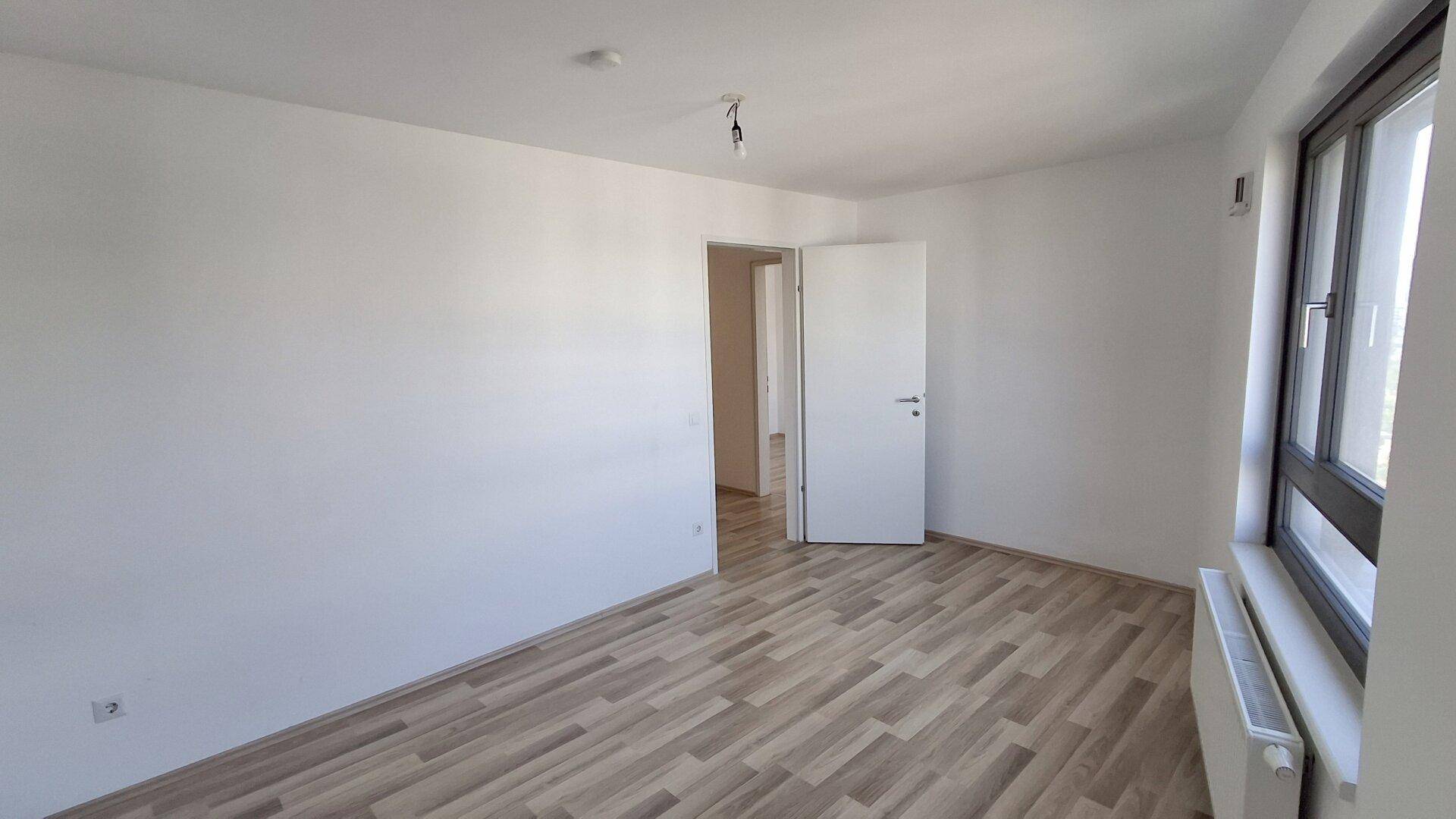 Unmöblierter Raum mit Laminatboden und weiß gestrichenen Wänden, bereit zur individuellen Gestaltung.