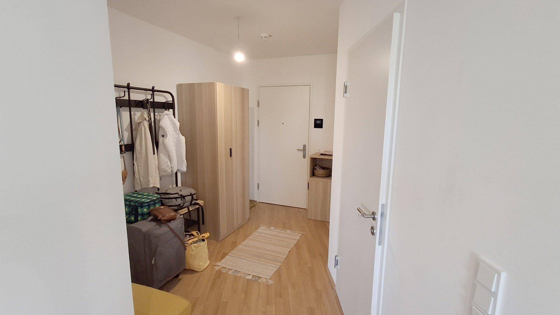 Eingangsbereich mit Garderobe, Schrank und hellem Holzfußboden.