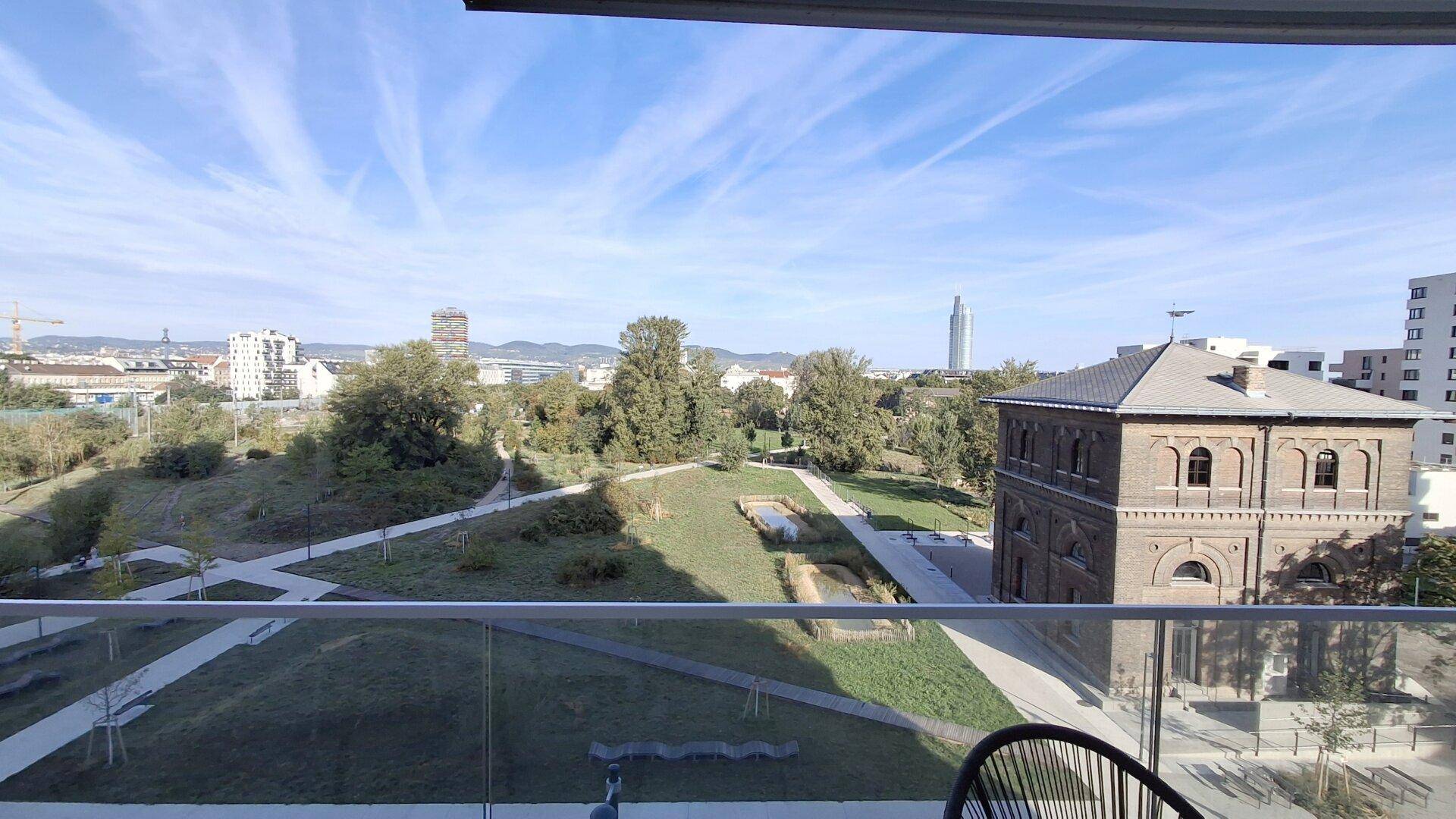 Balkon mit Panoramablick auf eine weitläufige Parkanlage, ein historisches Gebäude und die Stadt.
