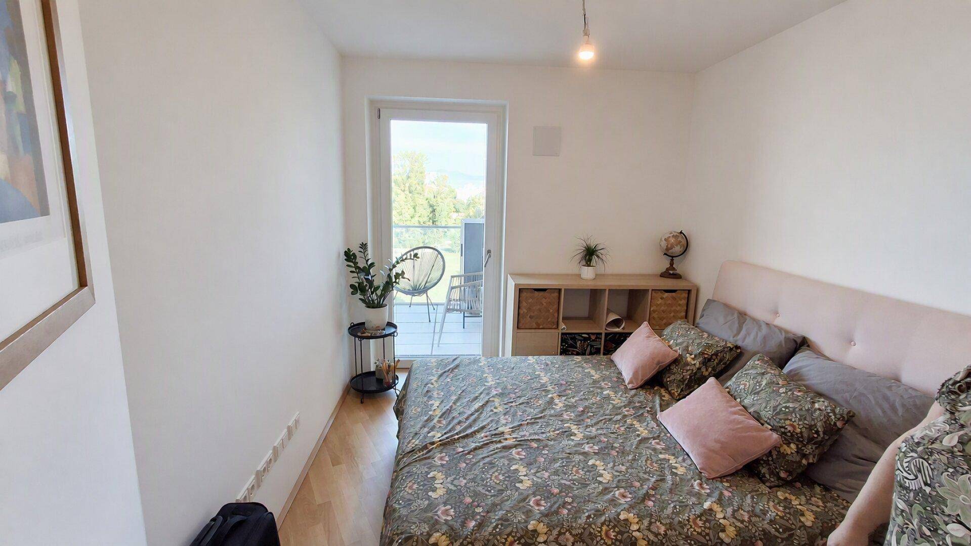 Gemütliches Schlafzimmer mit Doppelbett, Holzboden und Zugang zu einem Balkon.