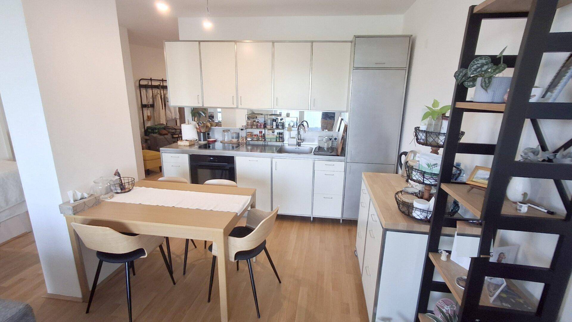 Moderne Einbauküche mit weißen Schränken, Essbereich und Holzboden.