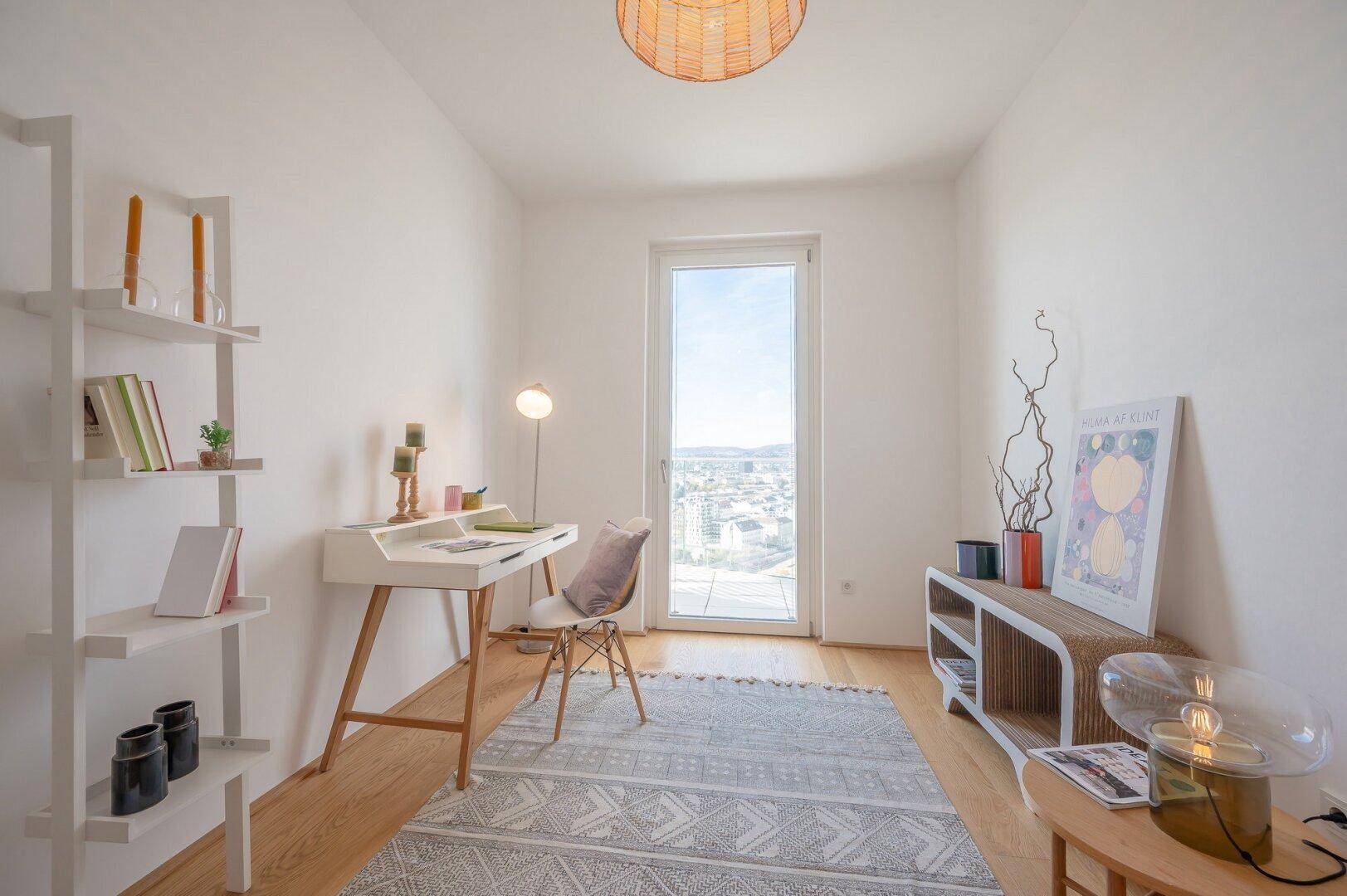 Helles Arbeitszimmer mit Holzboden, Schreibtisch und Fenster mit Fernblick.