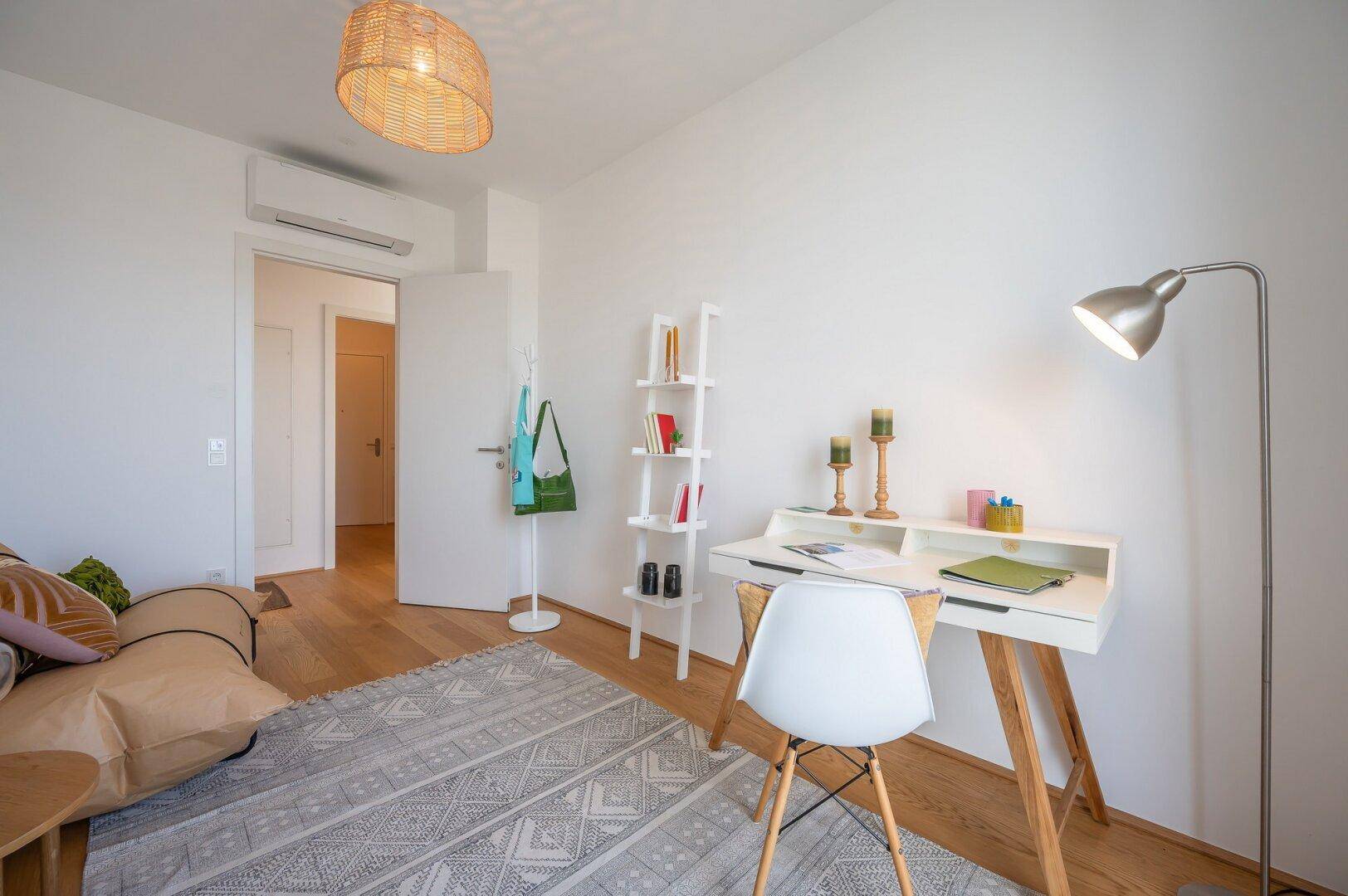 Modernes Arbeitszimmer mit Holzboden, Schreibtisch und Klimaanlage für angenehmes Raumklima.