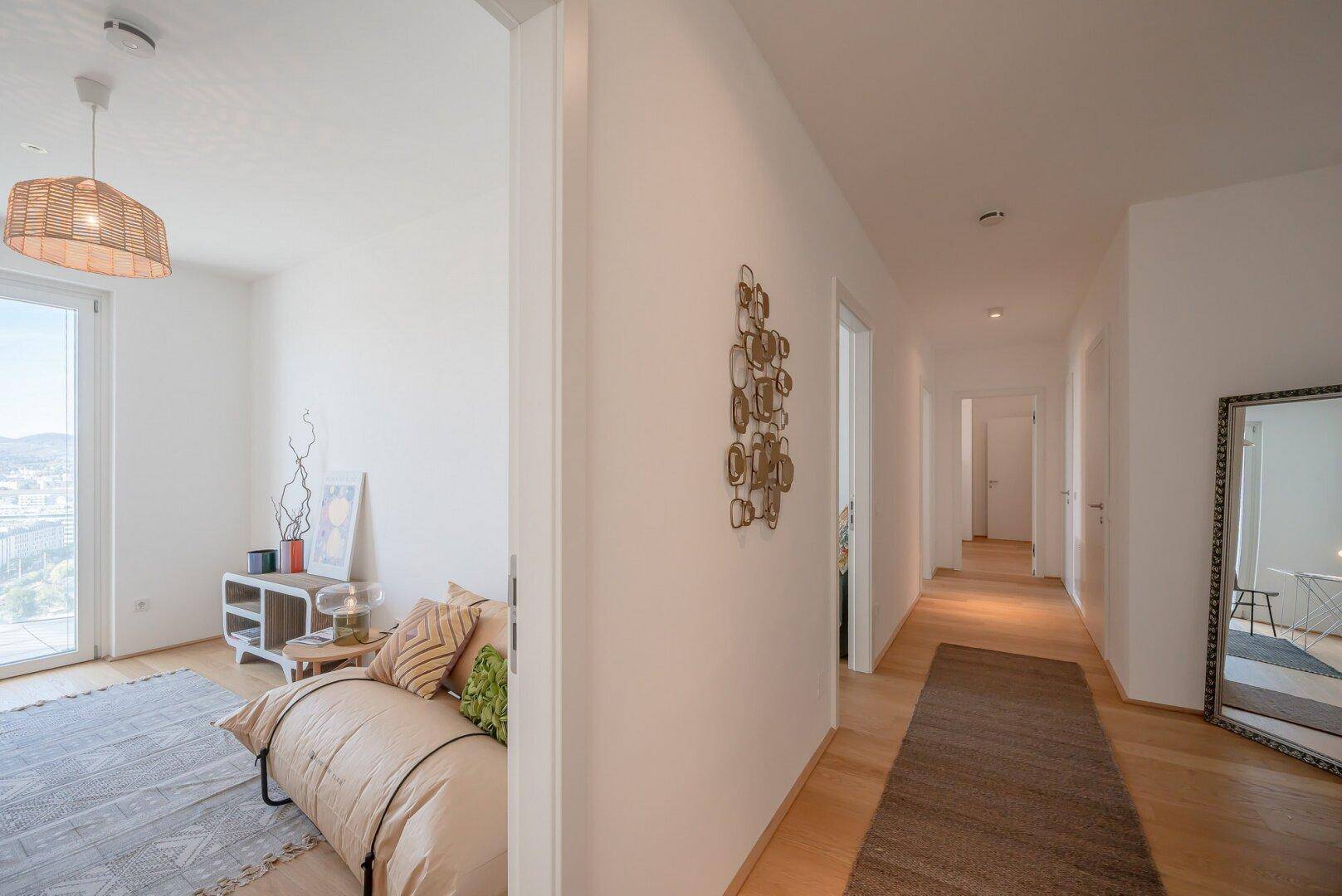 Heller Flur mit Holzboden, der zu den verschiedenen Zimmern der Wohnung führt.