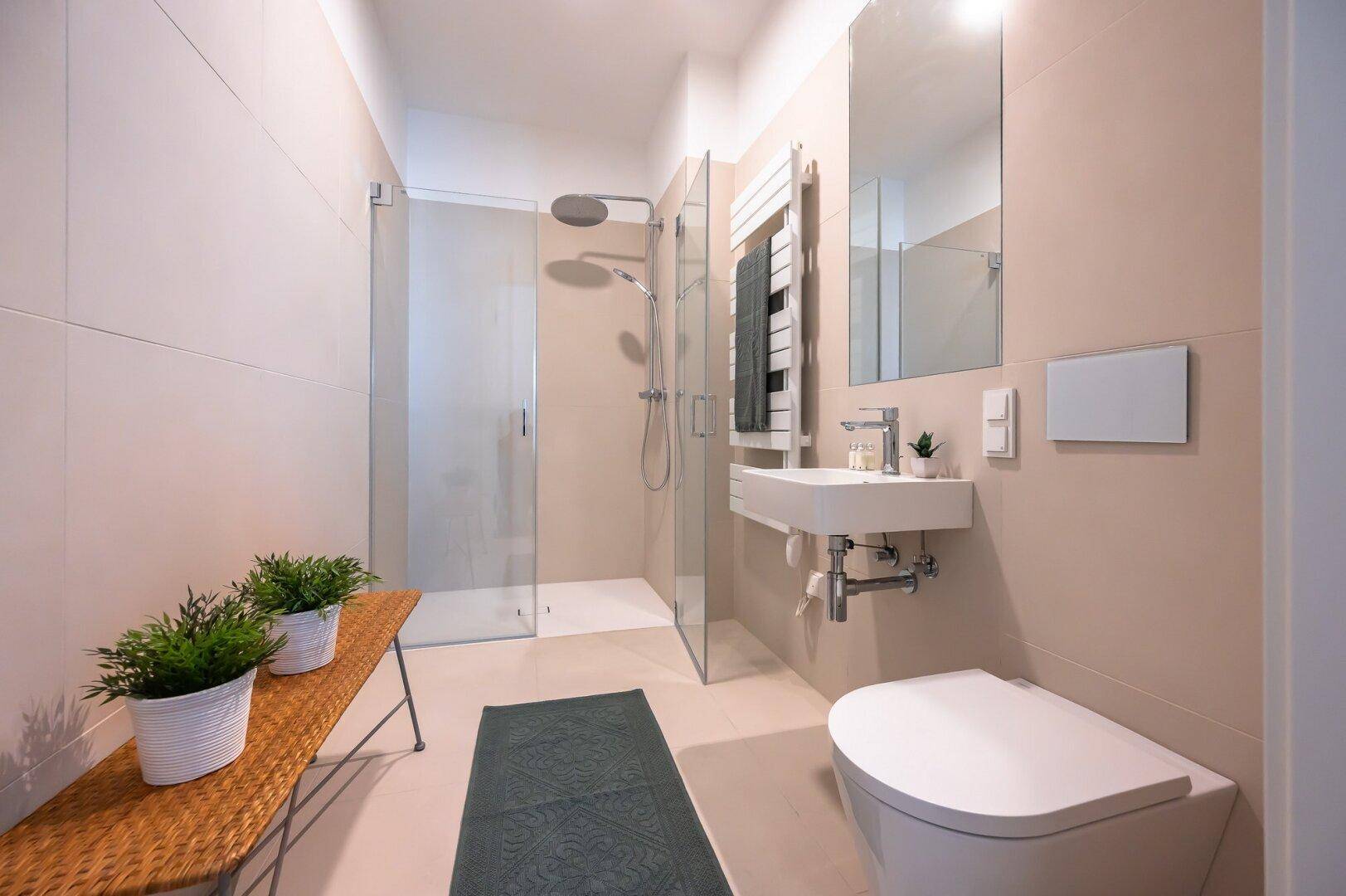 Modernes Badezimmer mit ebenerdiger Dusche, WC und beheiztem Handtuchhalter.