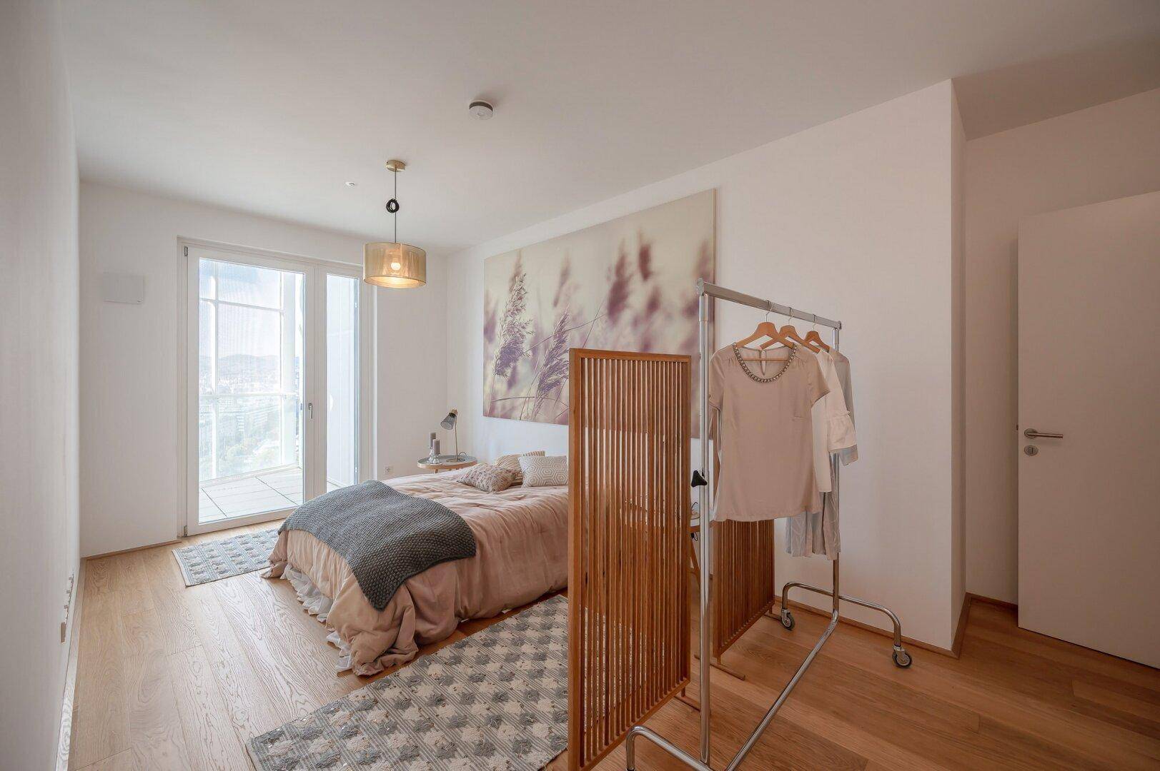 Geräumiges Schlafzimmer mit Doppelbett, Holzboden und Zugang zum Balkon.