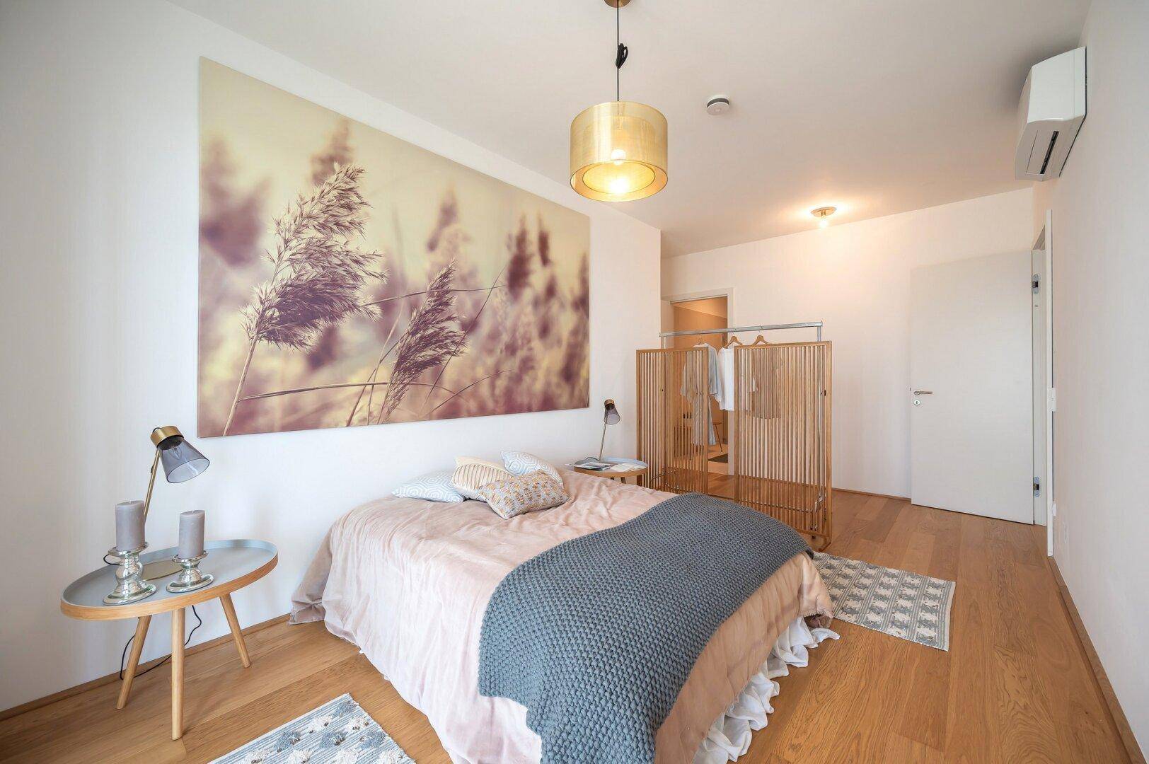 Helles Schlafzimmer mit Doppelbett, Holzboden und Klimaanlage.