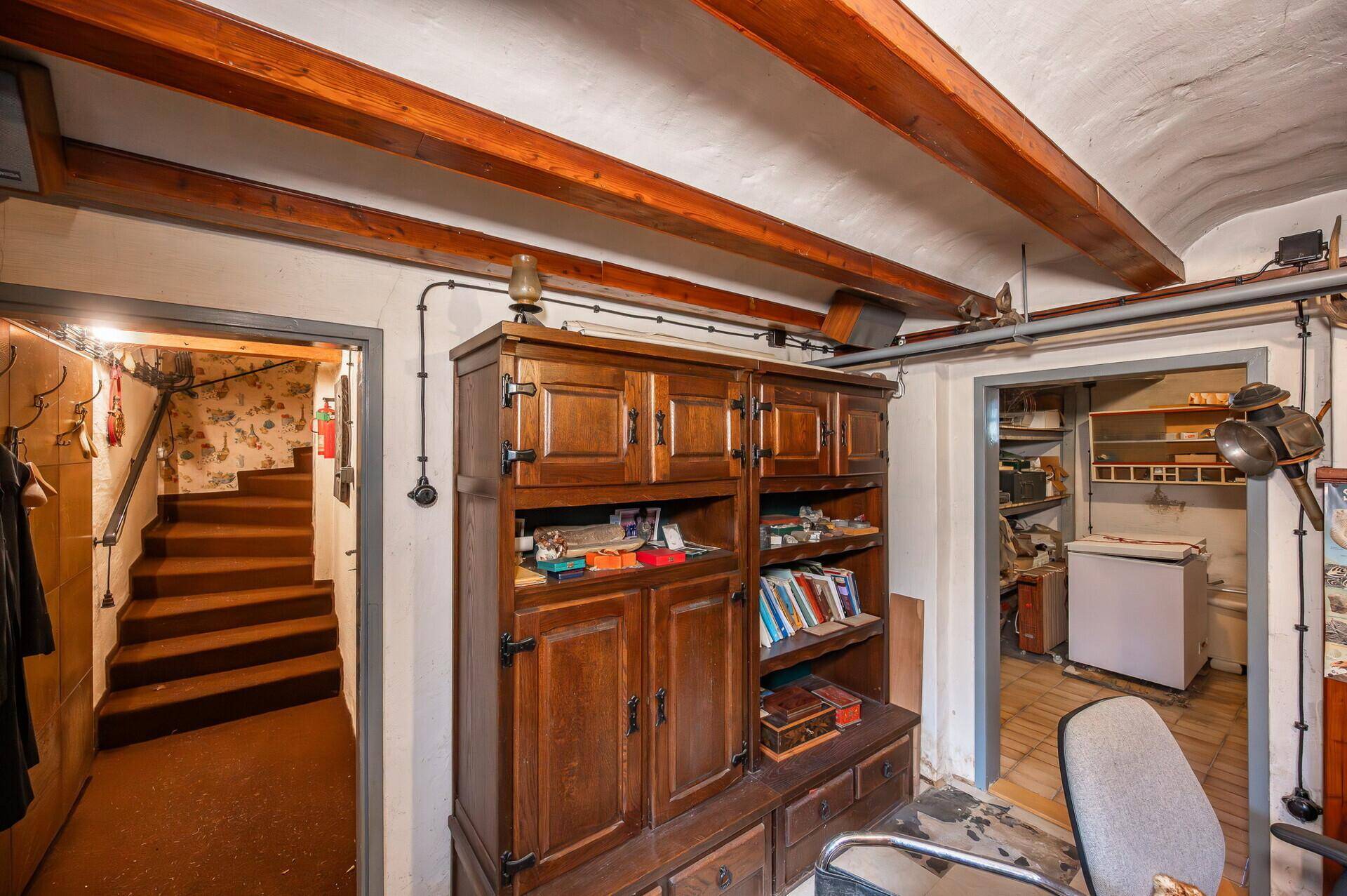 Kellerbereich mit einem großen Holzschrank und Zugang zu weiteren Abstellräumen.
