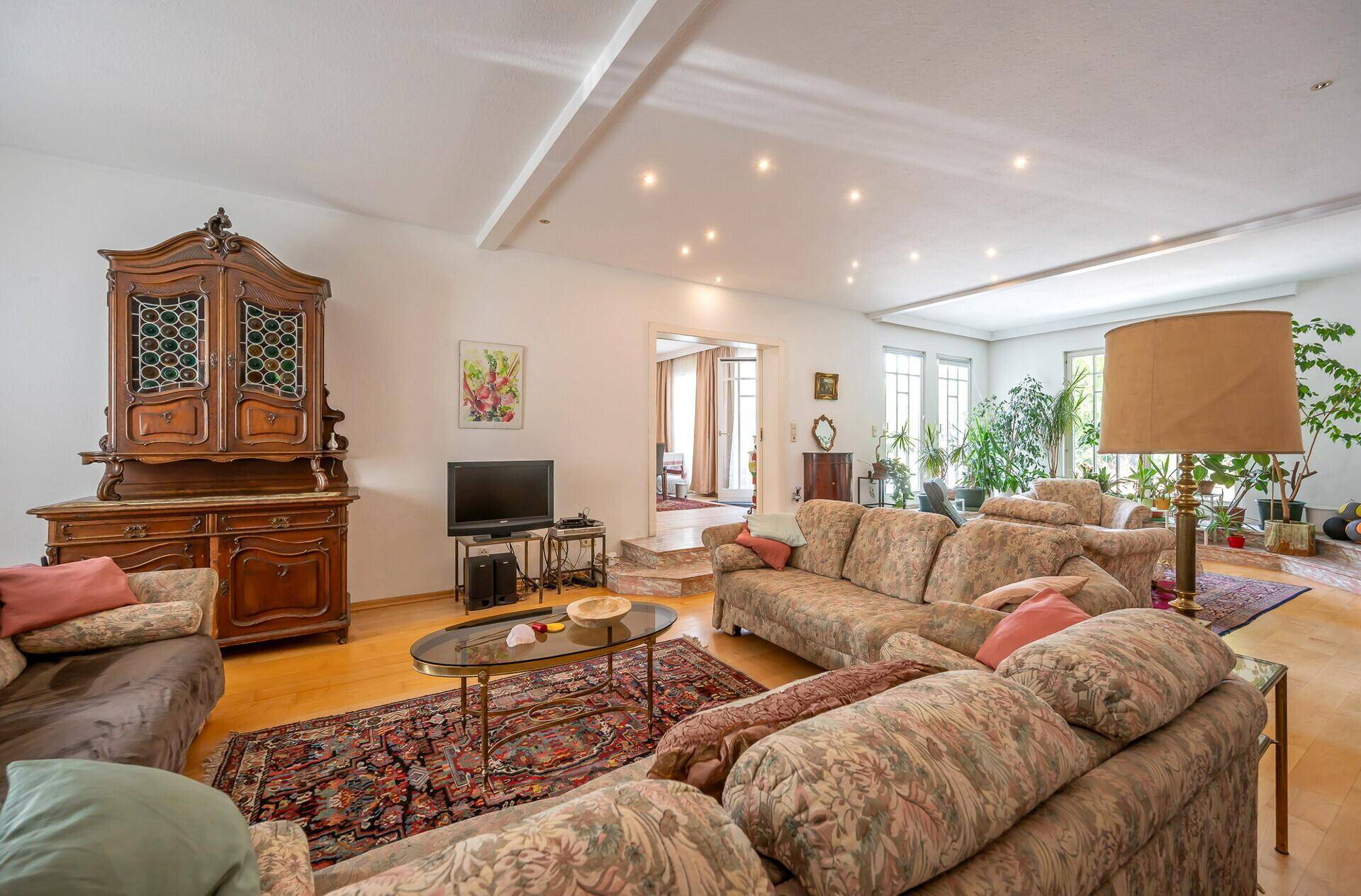 Großzügiges Wohnzimmer mit antiken Möbeln, Sofagarnitur und Parkettboden.