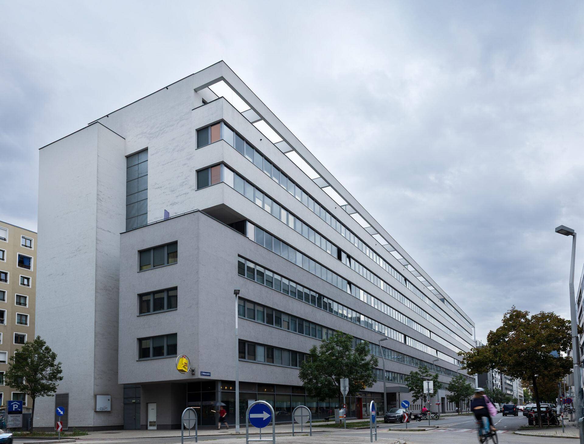 Ansicht eines modernen Bürogebäudes mit vielen Fenstern und klaren Linien an einem bewölkten Tag.