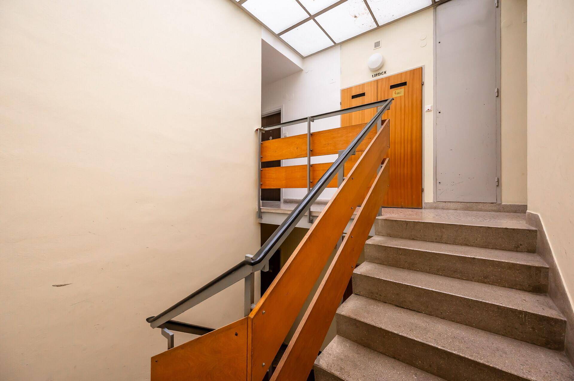Treppenhaus mit Holzgeländer und Oberlicht, das zu den oberen Etagen führt.