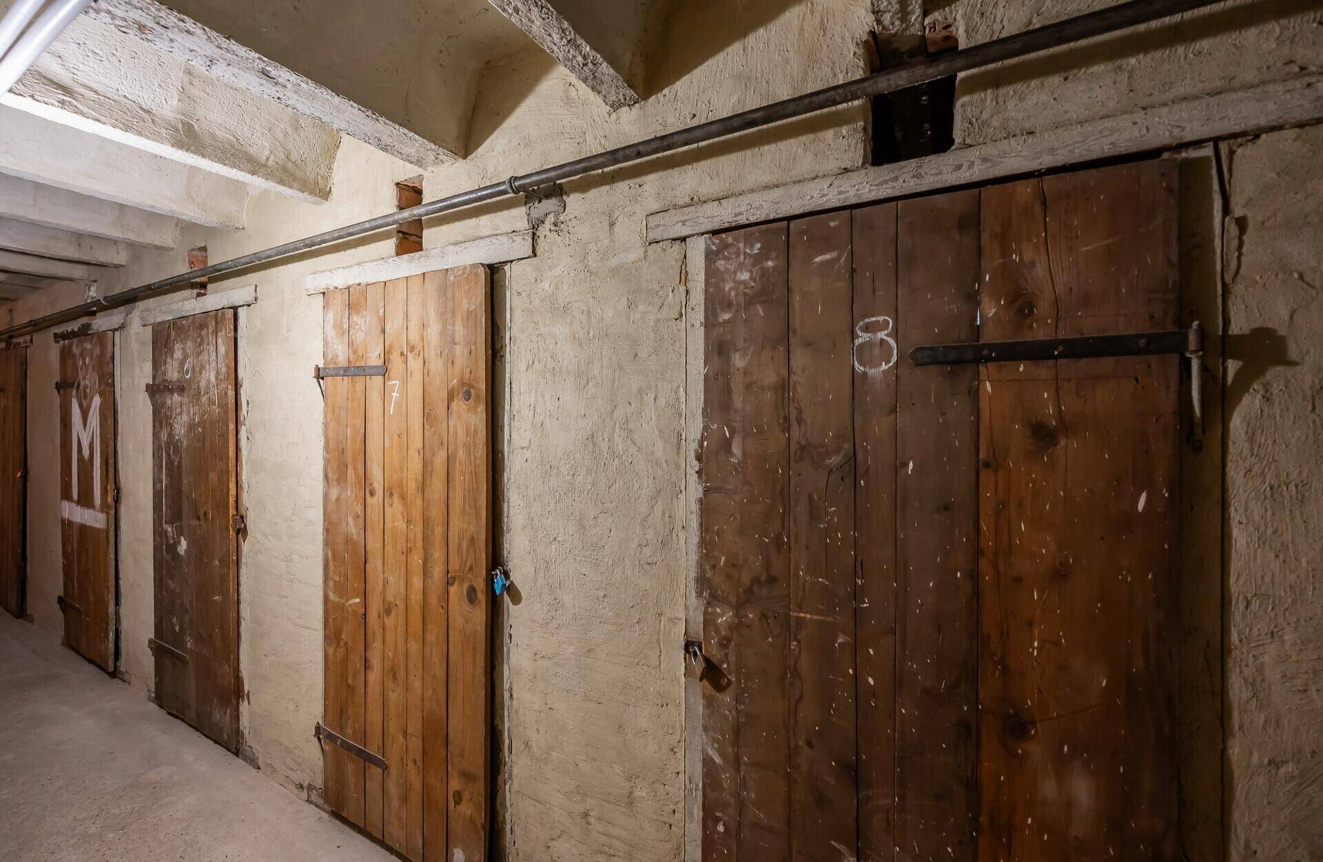 Kellerraum mit mehreren Holztüren zu Abstellkammern, typisch für ein Mehrfamilienhaus.