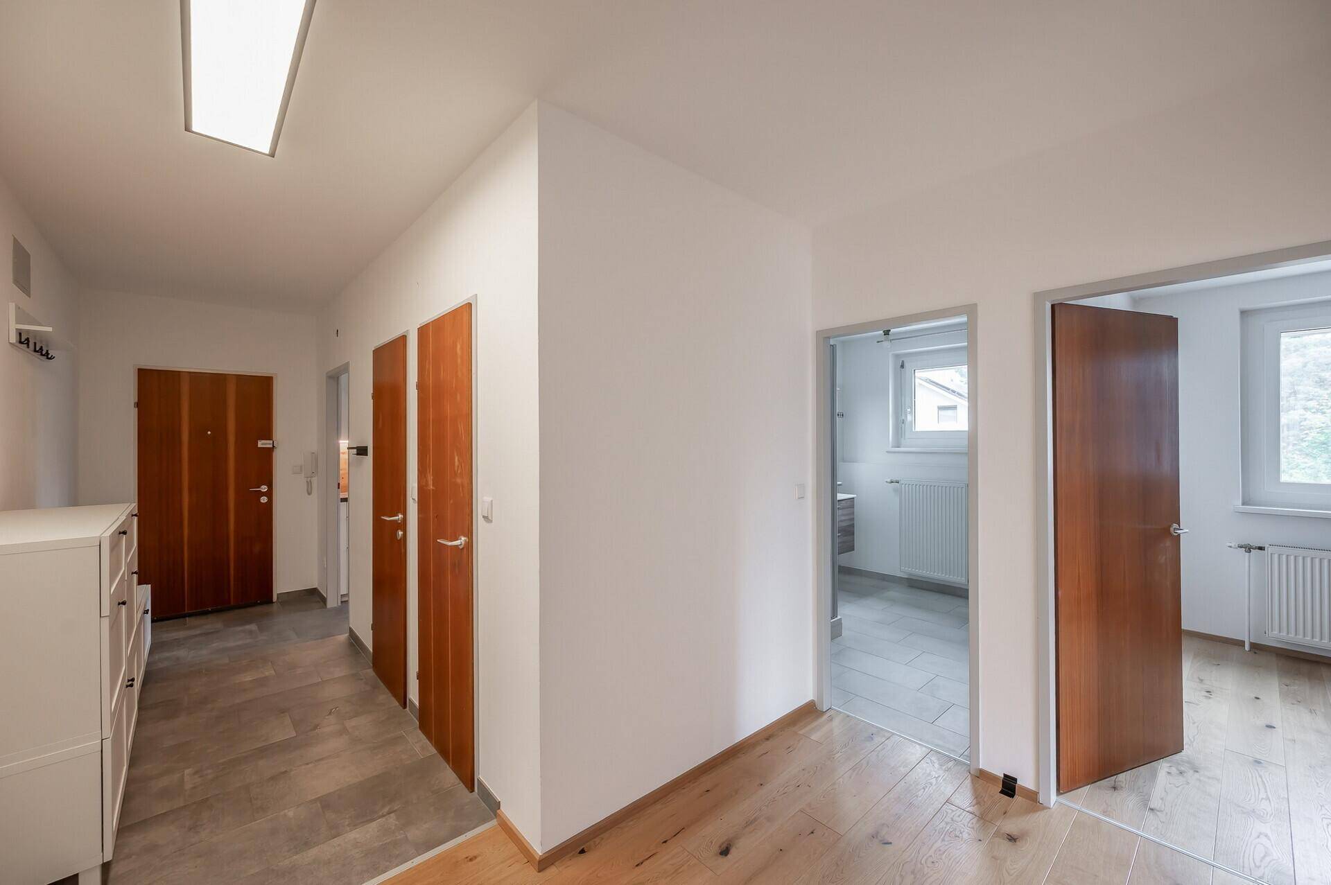 Heller Flur mit Holzfußboden, mehreren Holztüren und Zugang zu den Zimmern.
