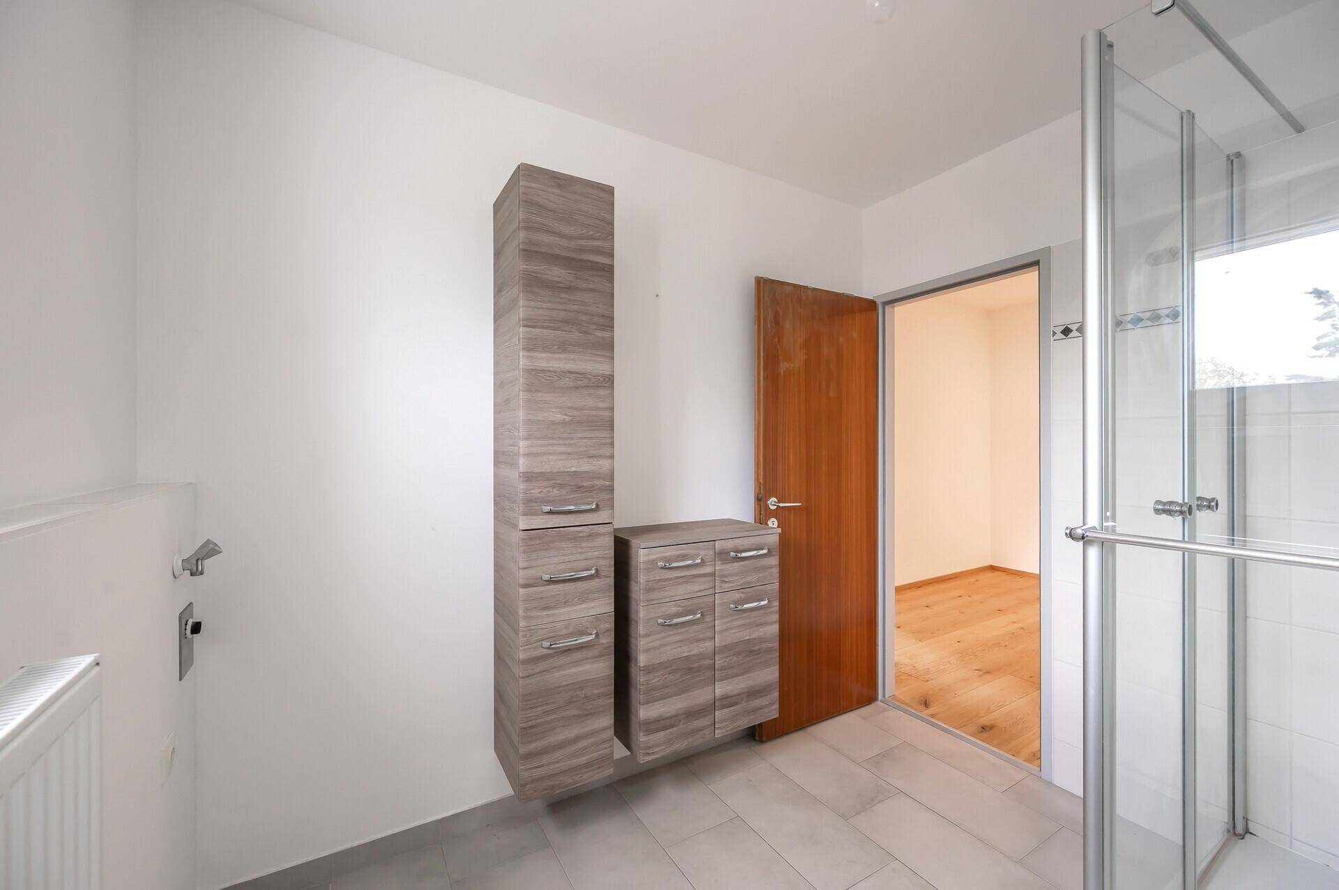 Badezimmer mit praktischen Holzschränken und Zugang zu einem weiteren Raum.