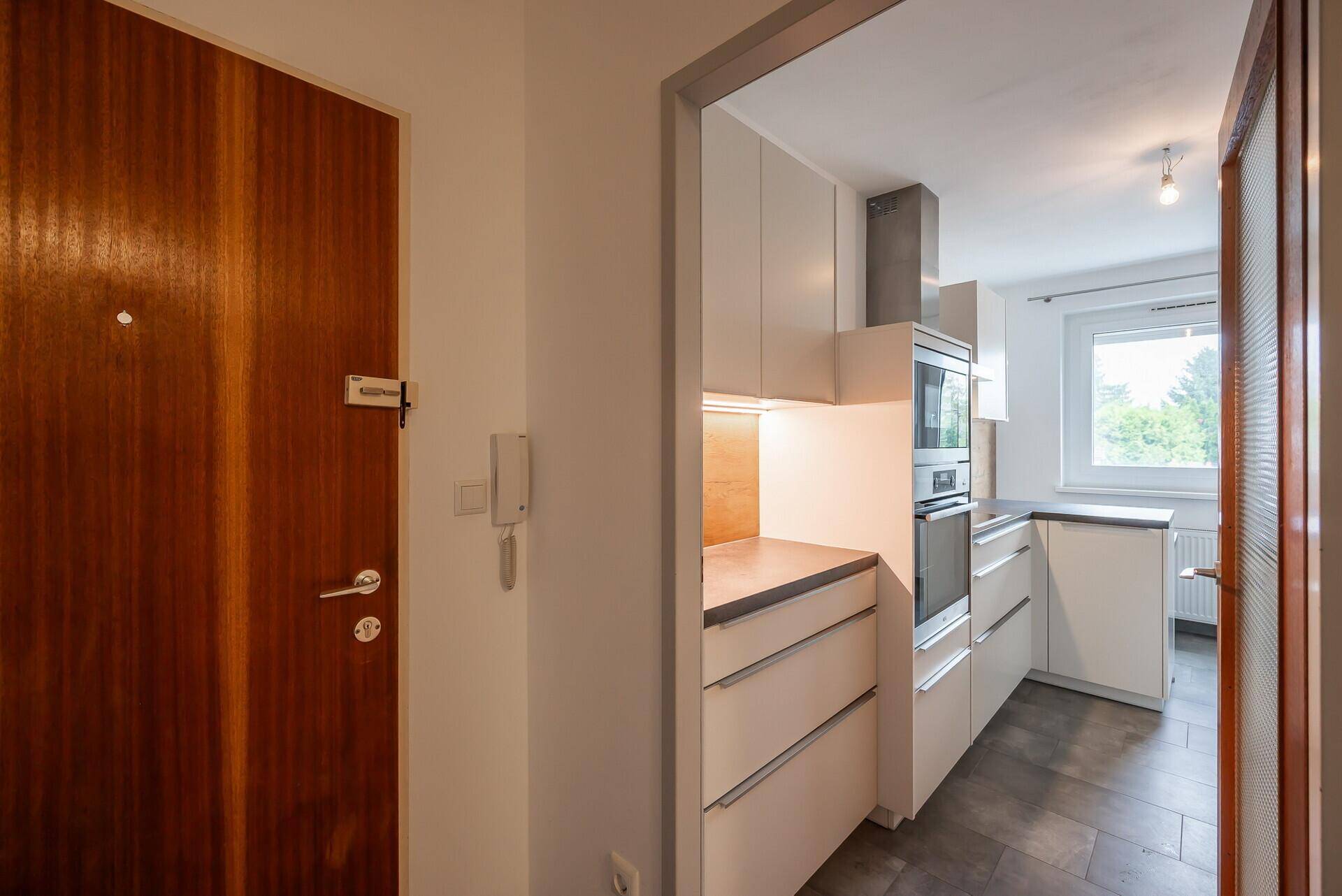 Eingangsbereich mit Holztür und direktem Zugang zur modernen Küche.