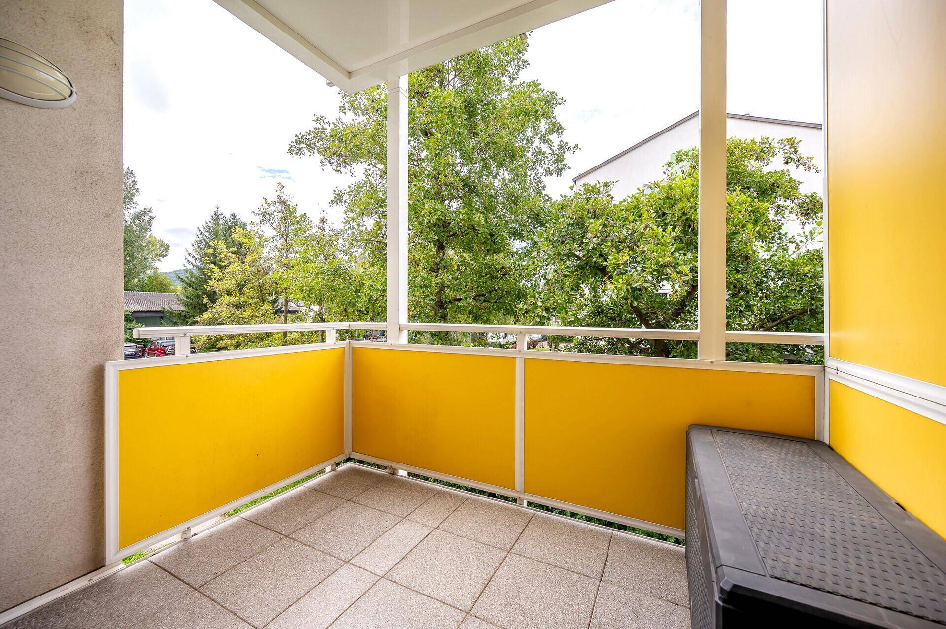 Geräumiger Balkon mit gelben Paneelen und weitem Blick auf die umliegende Natur.