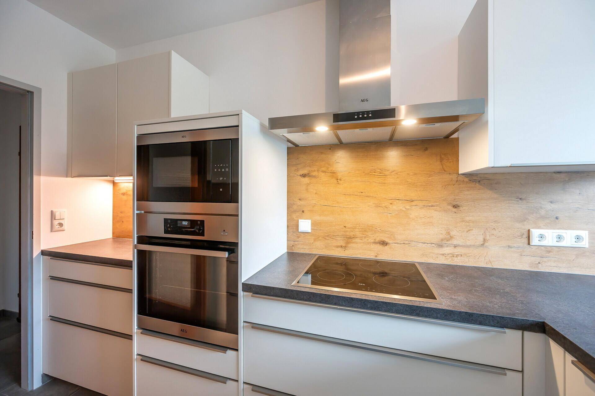 Detailansicht der Küche mit integriertem Backofen, Mikrowelle und Induktionskochfeld.