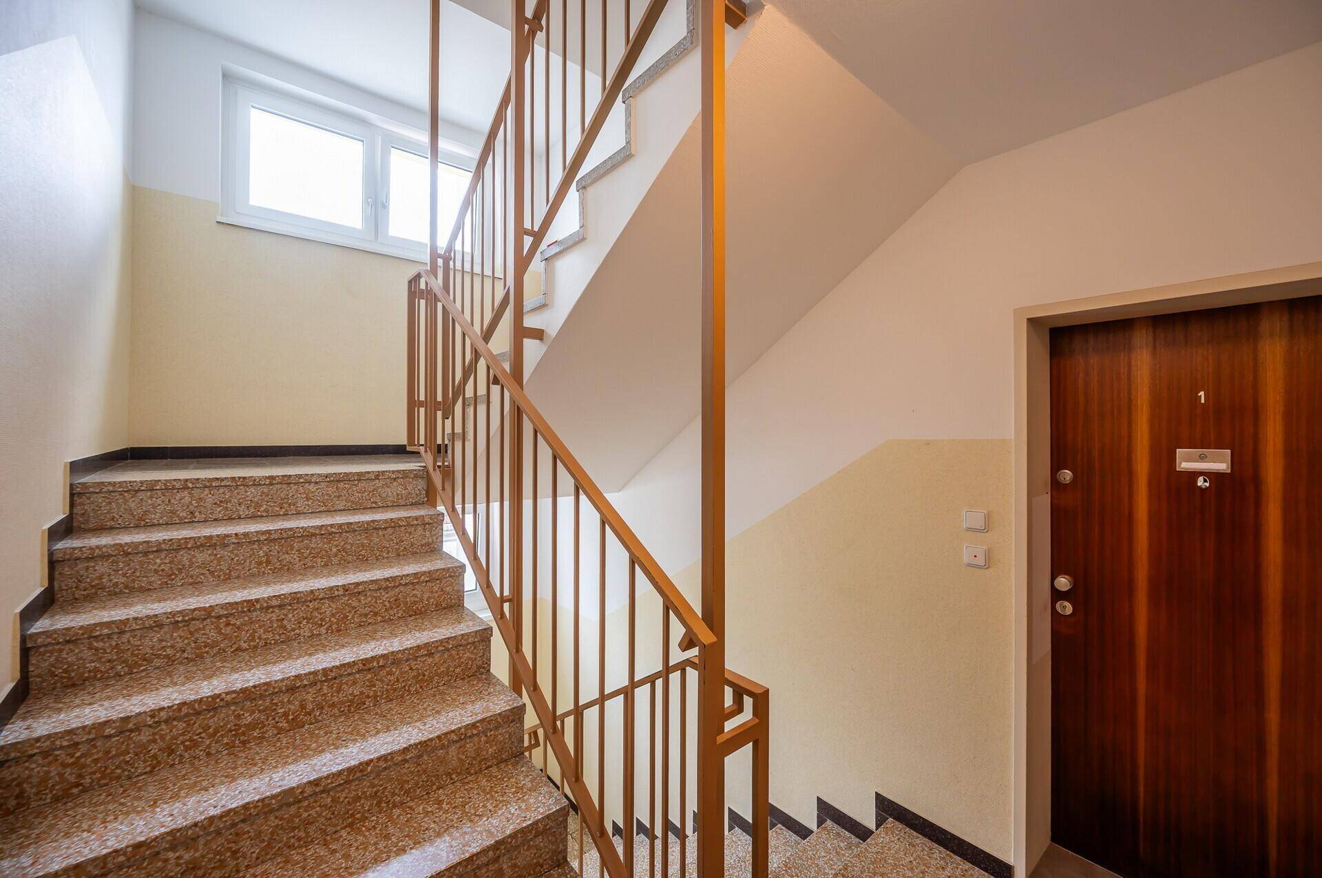 Treppenhaus mit Granitstufen und Metallgeländer in einem Mehrfamilienhaus.