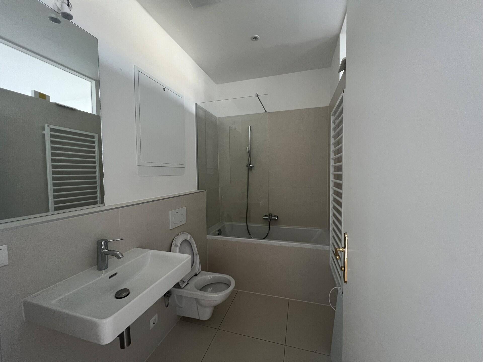 Modernes Badezimmer mit Badewanne, WC, Waschbecken und praktischem Handtuchheizkörper.