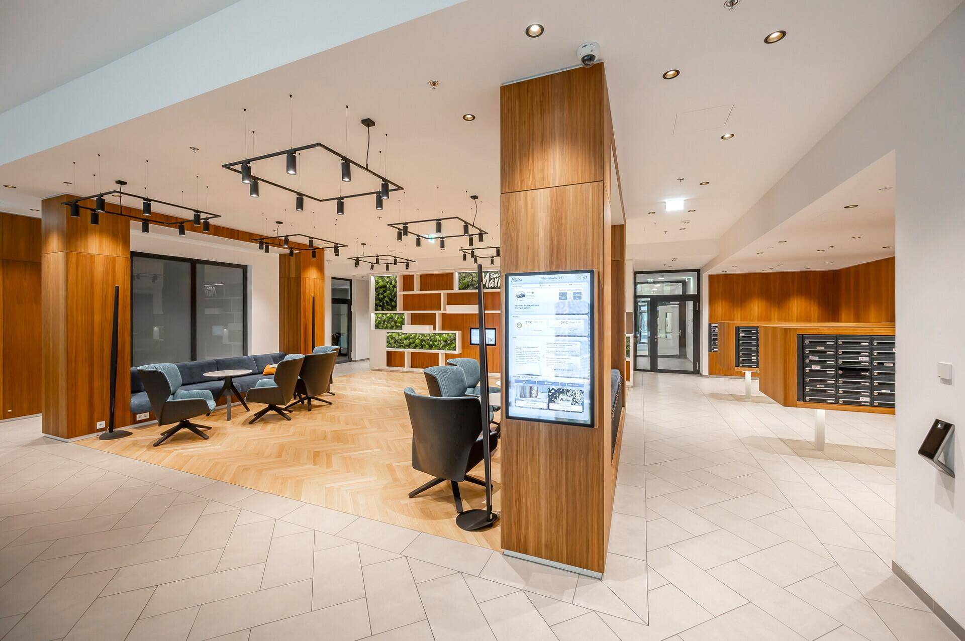 Moderne Lobby mit Sitzgelegenheiten, Holzakzenten und digitalen Informationsbildschirmen.