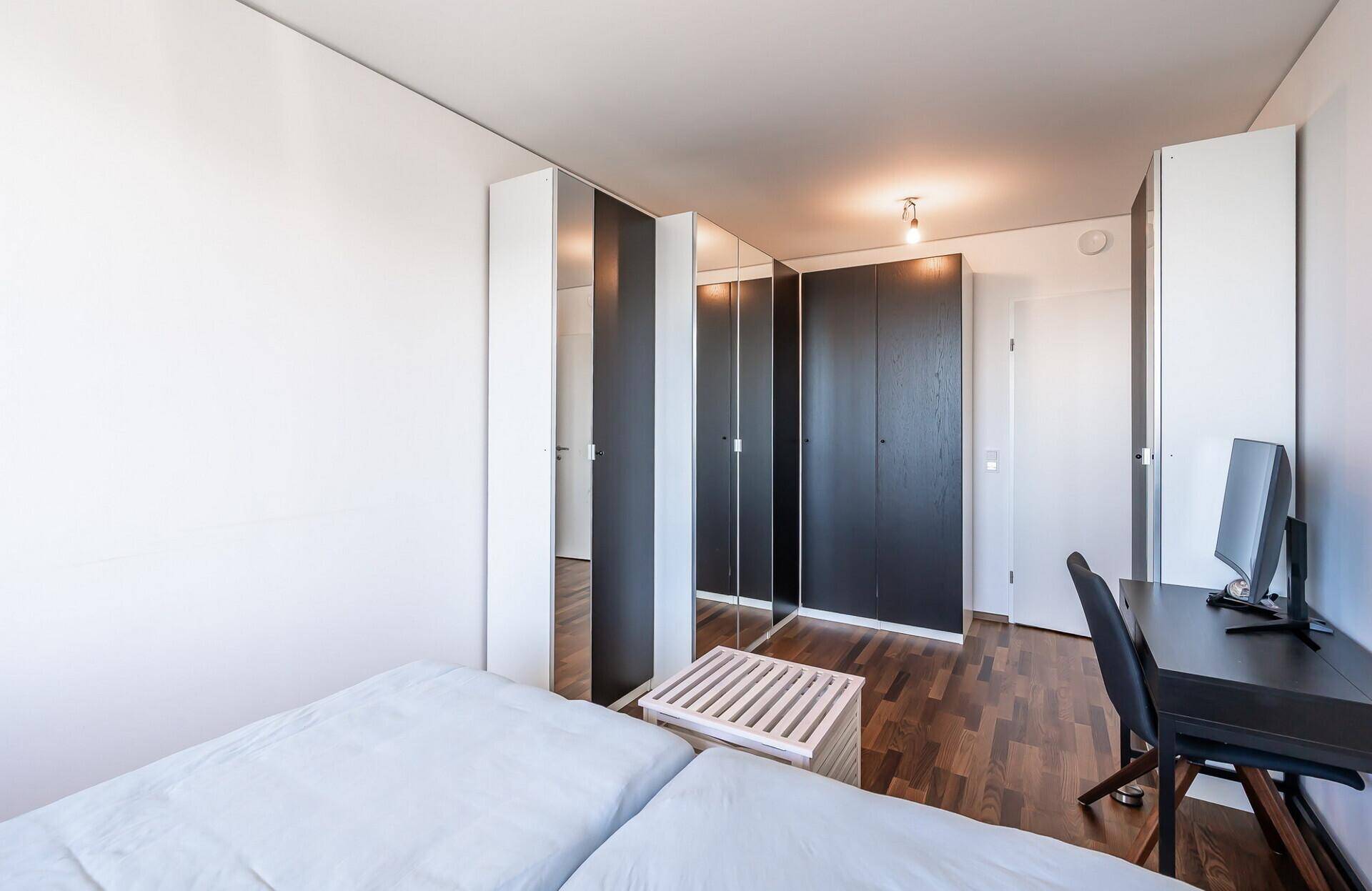 Schlafzimmer mit Holzboden und einer Wand aus praktischen Kleiderschränken.