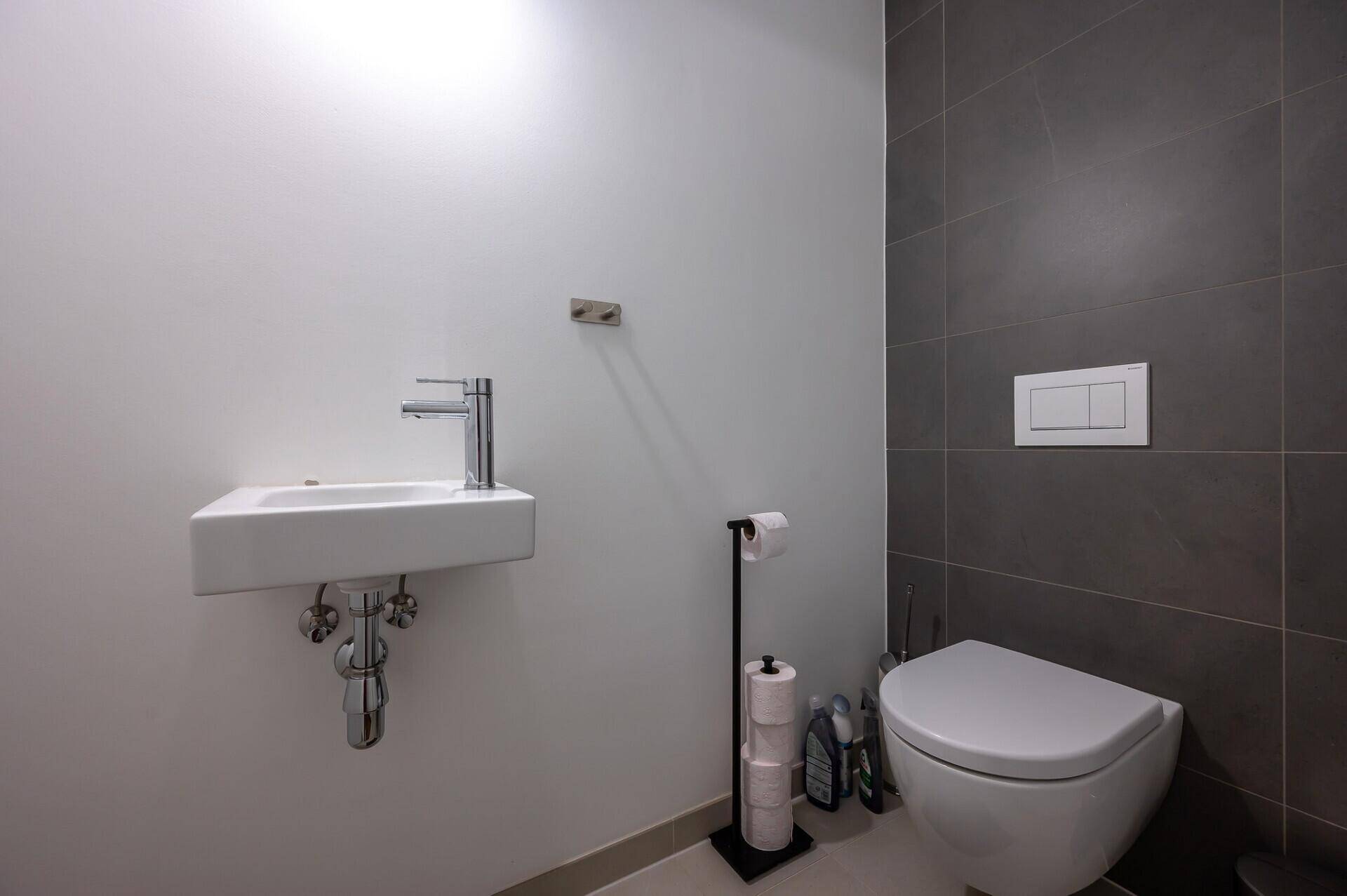 Modernes Gäste-WC mit kleinem Waschbecken und Wand-WC in schlichtem Design.