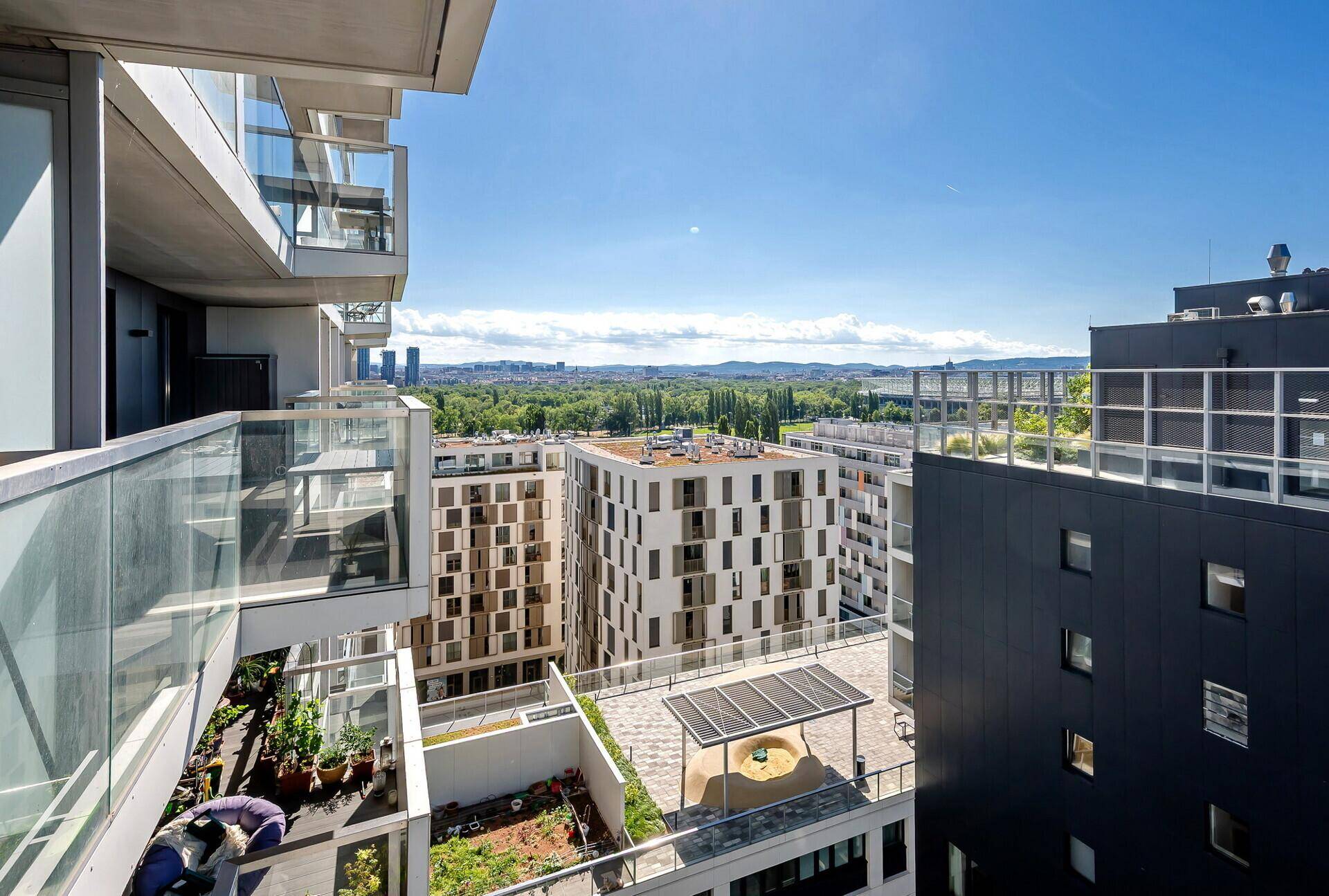 Blick von oben auf moderne Wohngebäude und begrünte Dachterrassen in der Umgebung.