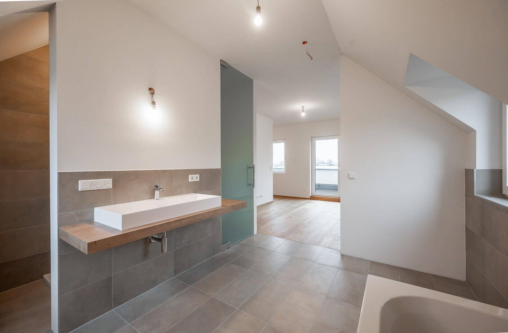 Großes Badezimmer im Dachgeschoss mit Badewanne, Dusche und Einzelwaschbecken.