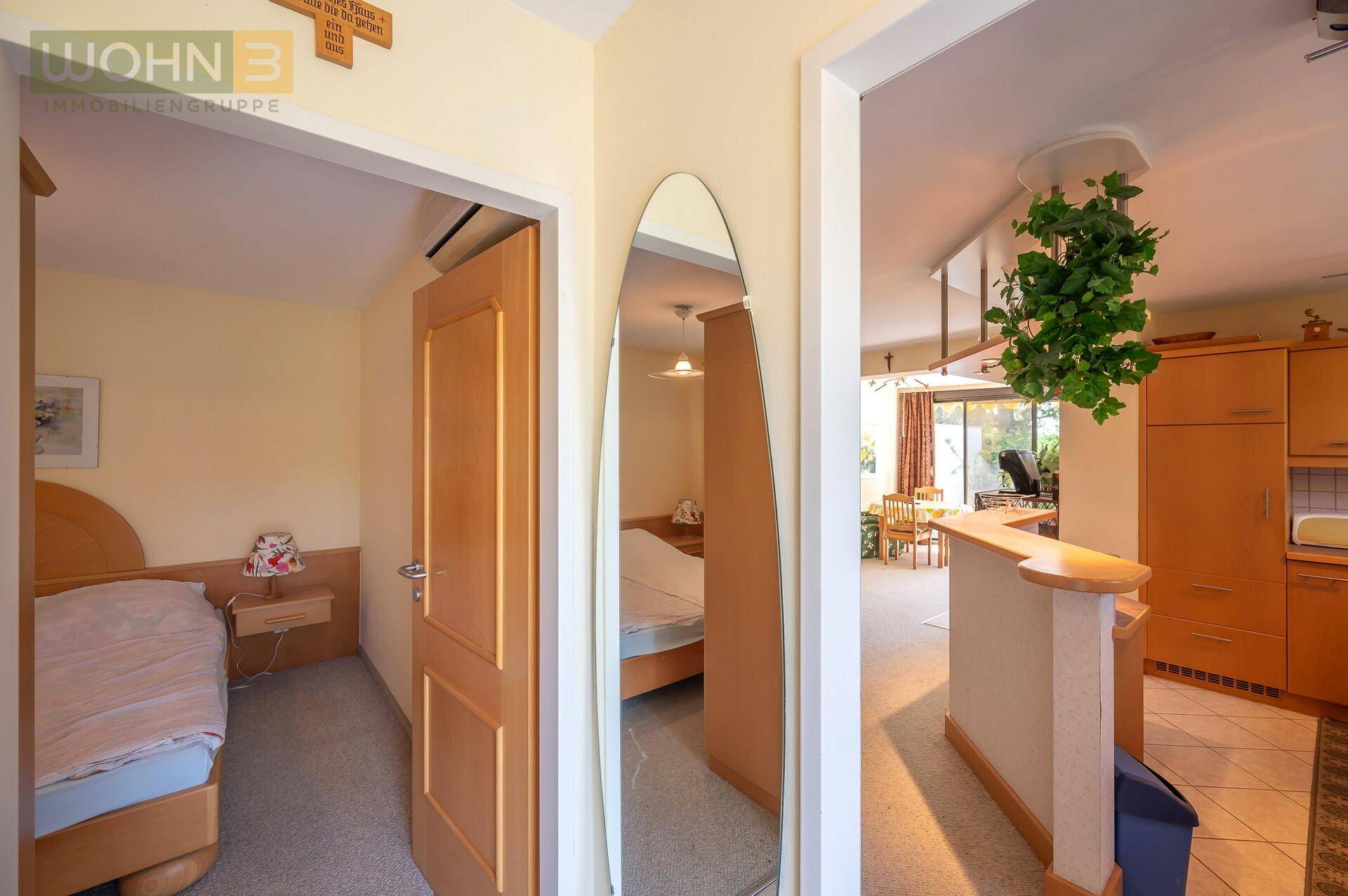 Heller Flur mit großem Spiegel, der den Blick auf Schlafzimmer und Wohnbereich freigibt.