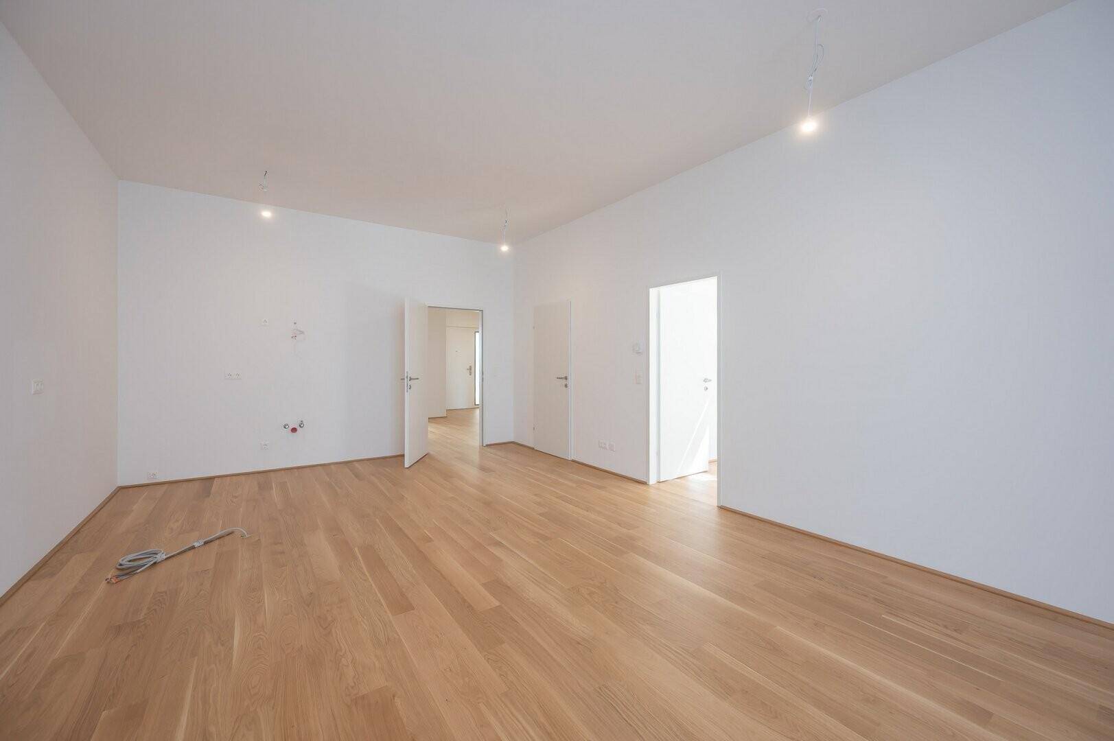 Leerer Raum mit hellem Holzboden und weißen Wänden, bereit zur individuellen Gestaltung.