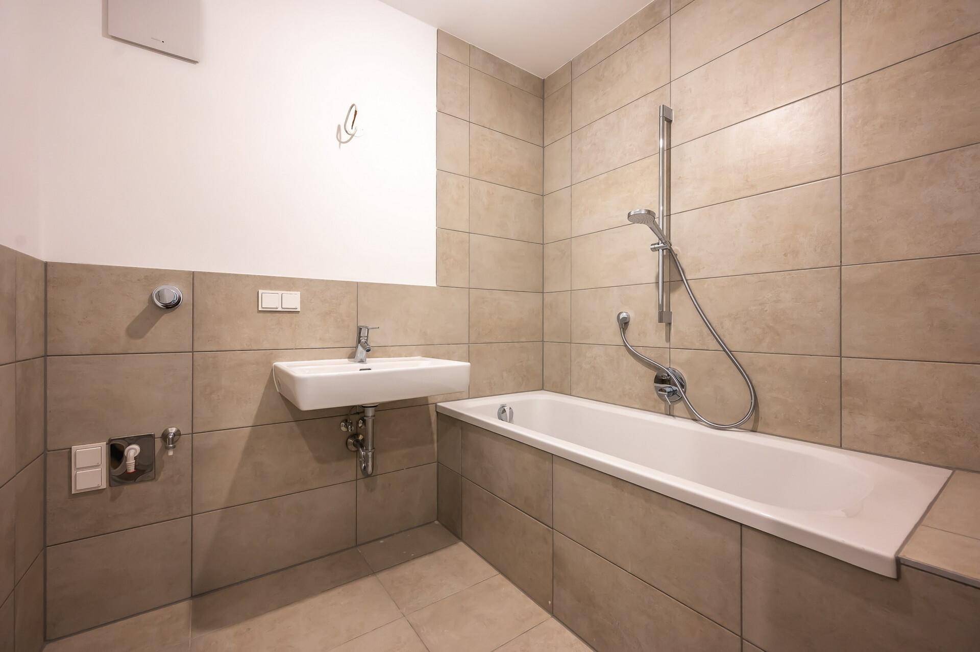 Modernes Badezimmer mit Badewanne, Waschbecken und beigefarbenen Fliesen.