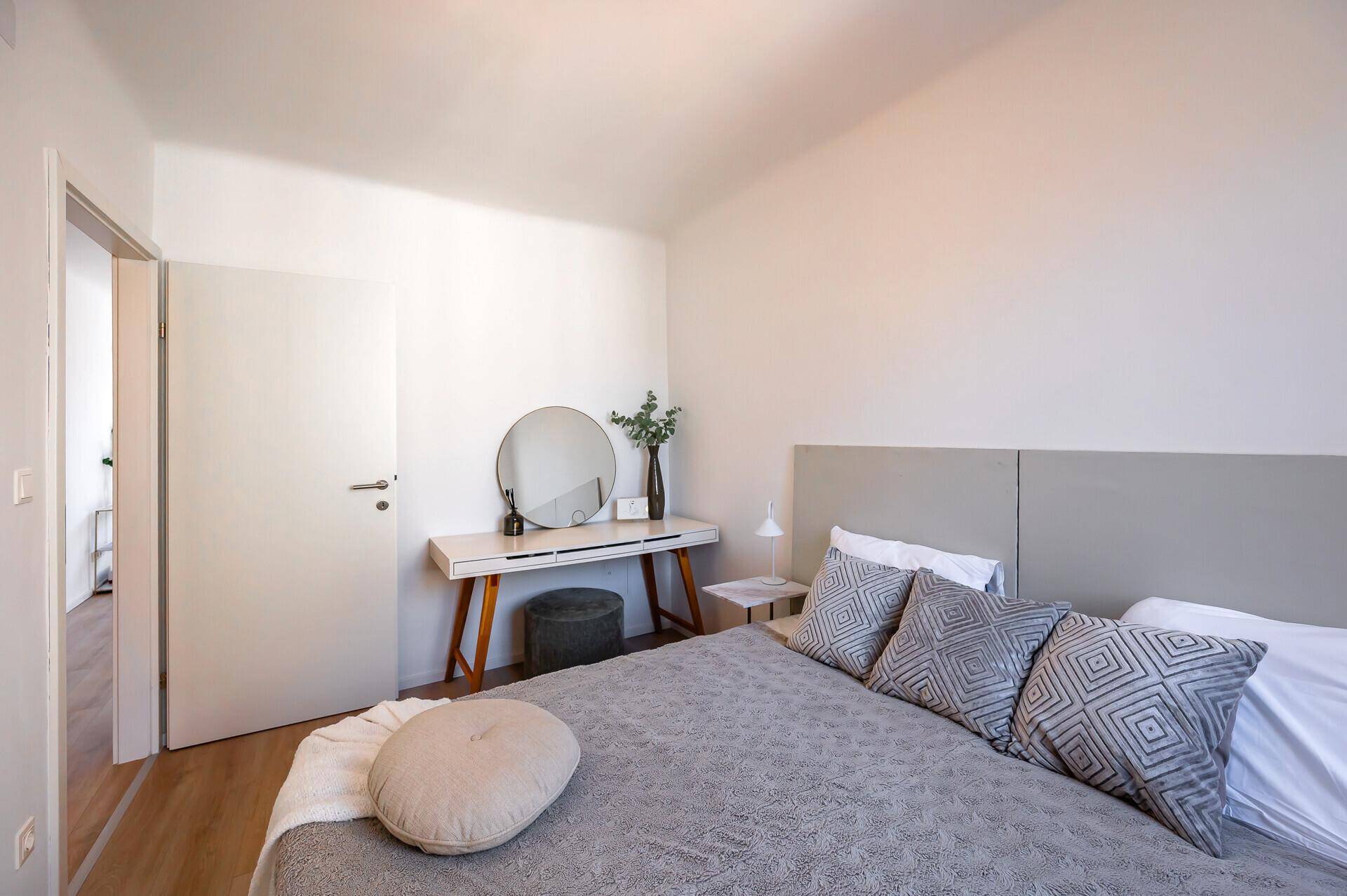 Schlafzimmer mit modernem Bett, Schminktisch und Zugang zum Flur.