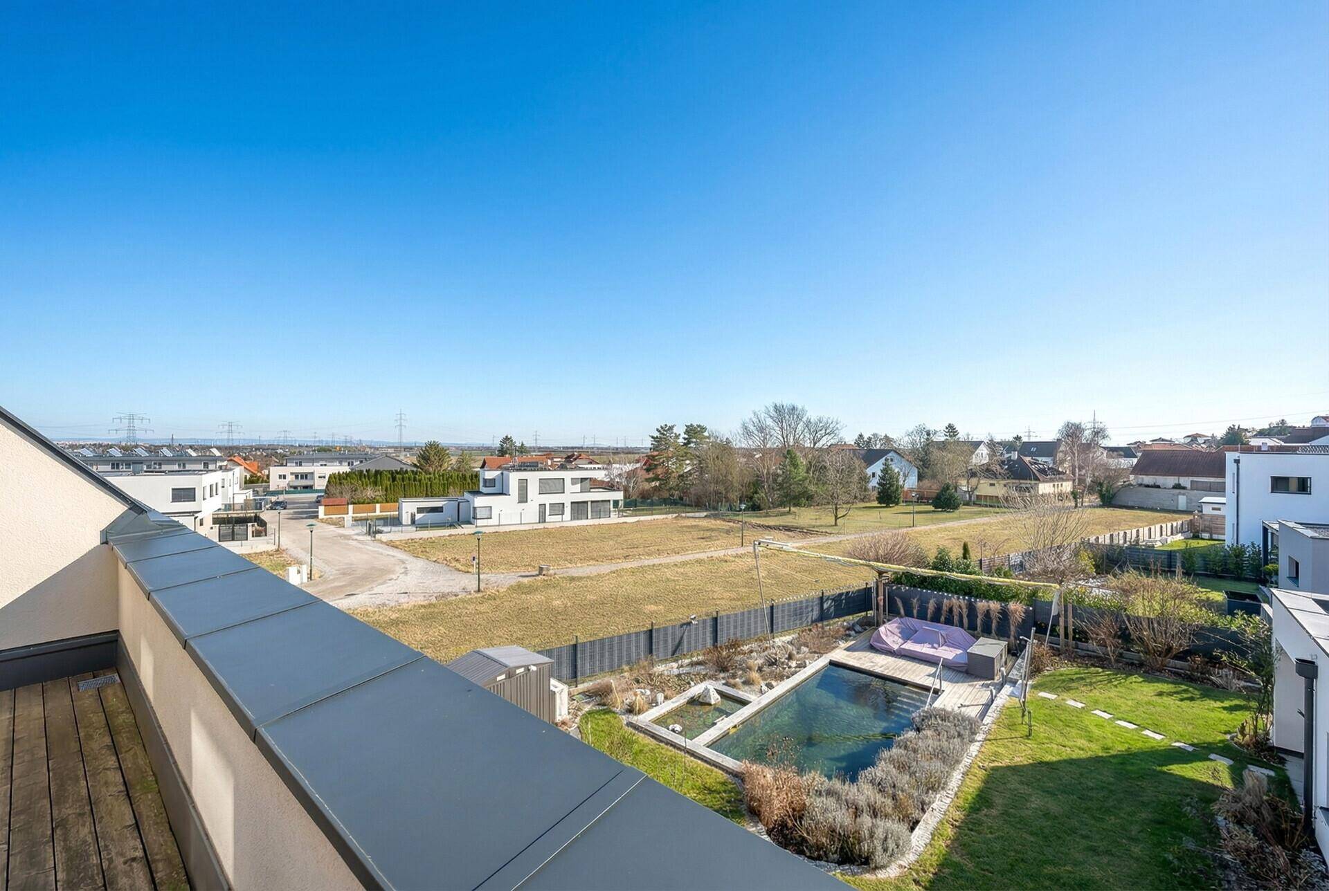 Dachterrasse mit Holzboden und Panoramablick auf die umliegende Landschaft und einen Pool.