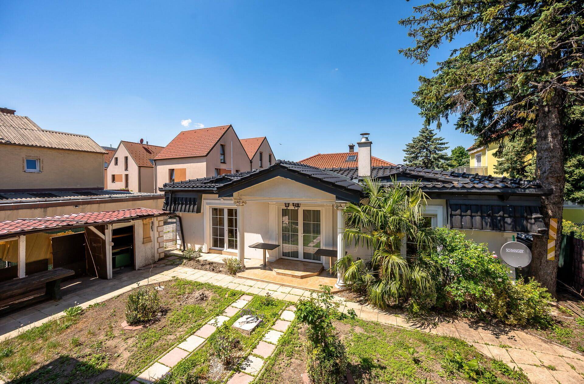 Überblick über den hinteren Gartenbereich mit Anbau, Terrasse und umliegenden Häusern.