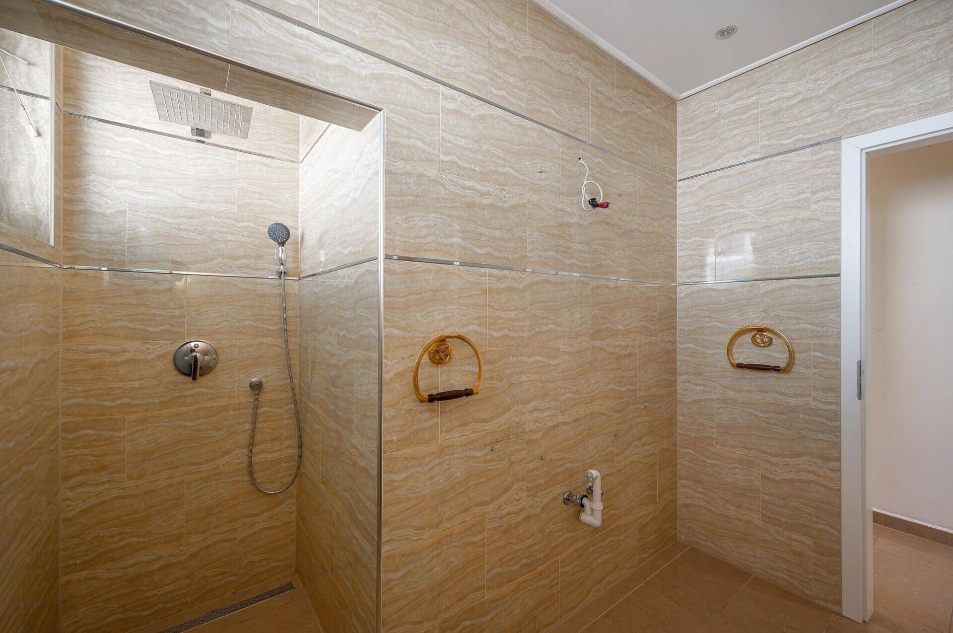 Geräumige Duschkabine im modernen Badezimmer mit beigen Fliesen und Regendusche.