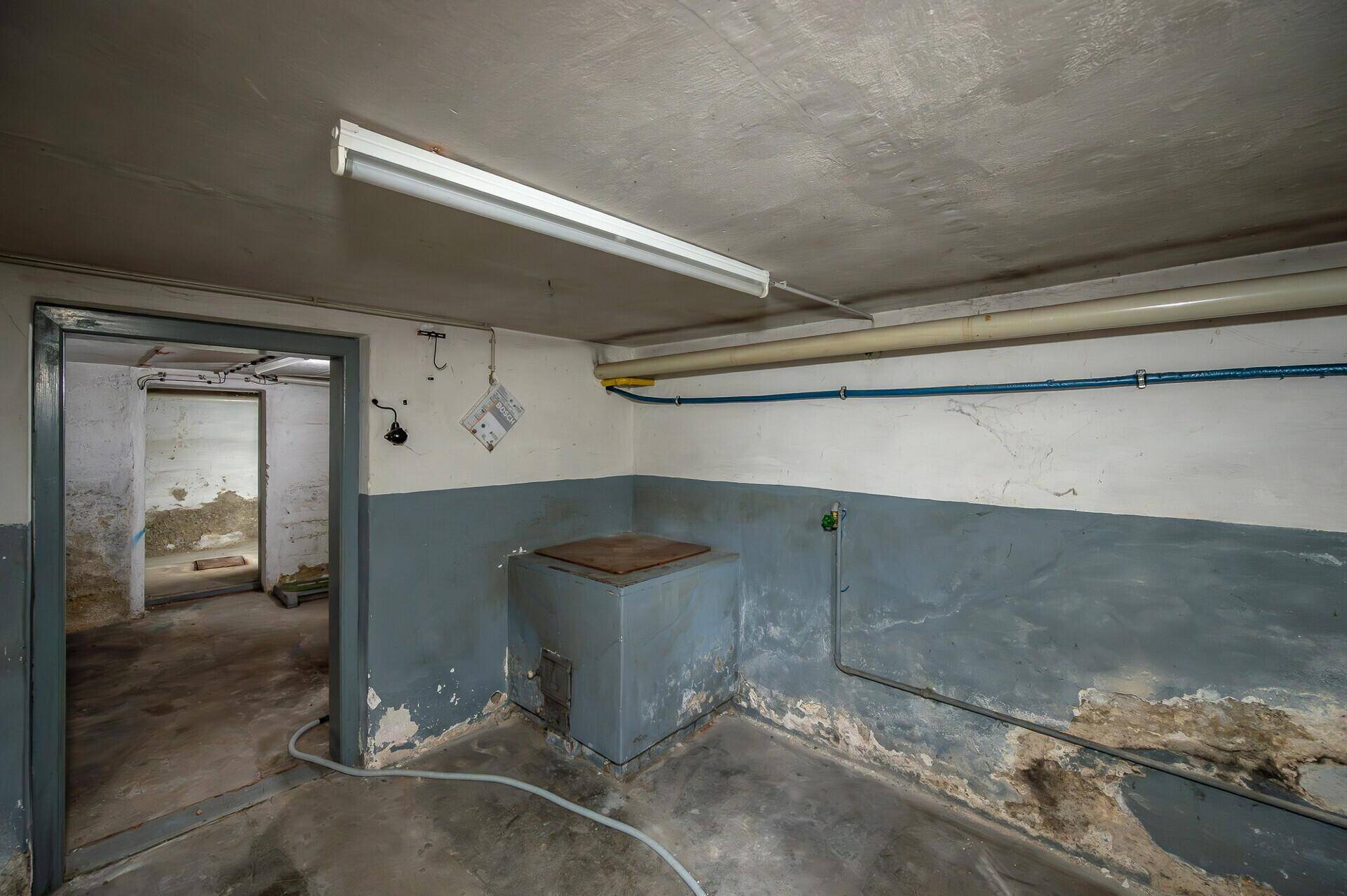 Kellerraum mit grauen Wänden und Betonboden, ideal als Abstellfläche.