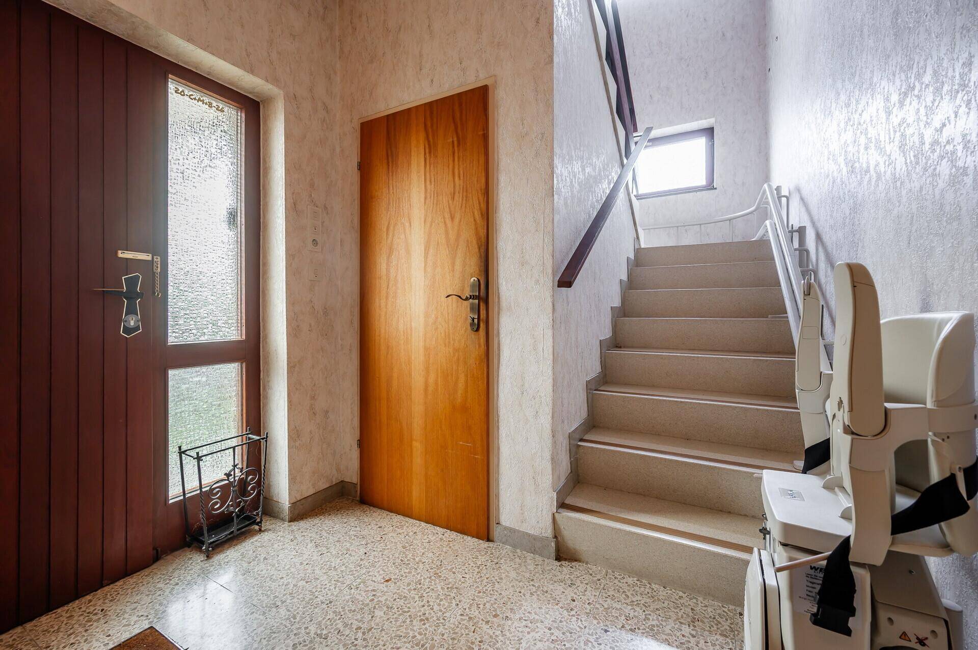 Eingangsbereich mit Treppe, die zu den oberen Etagen führt, und einem installierten Treppenlift.