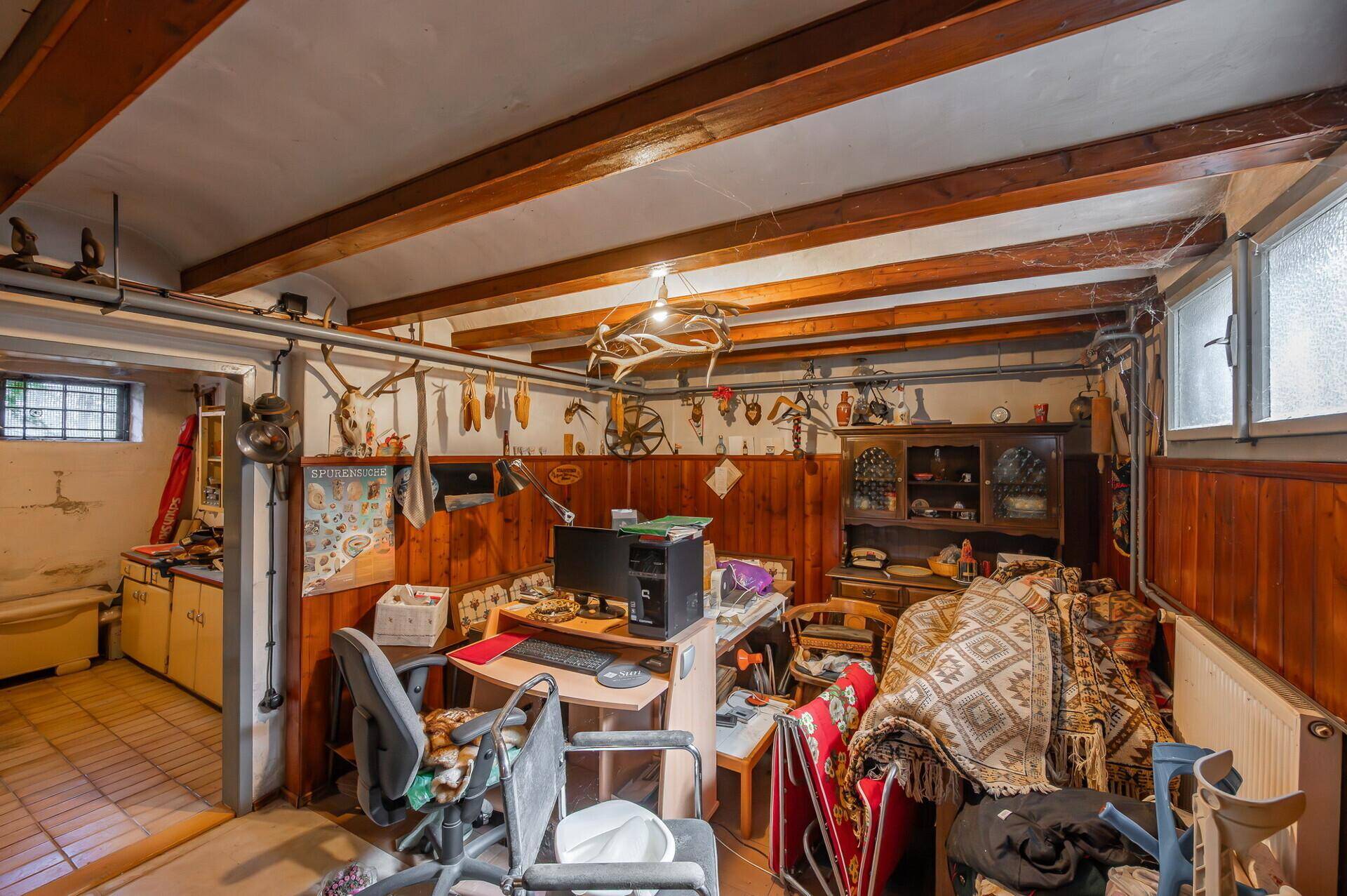 Rustikaler Raum mit Holzvertäfelung, sichtbaren Deckenbalken und zahlreichen Jagdtrophäen an den Wänden.