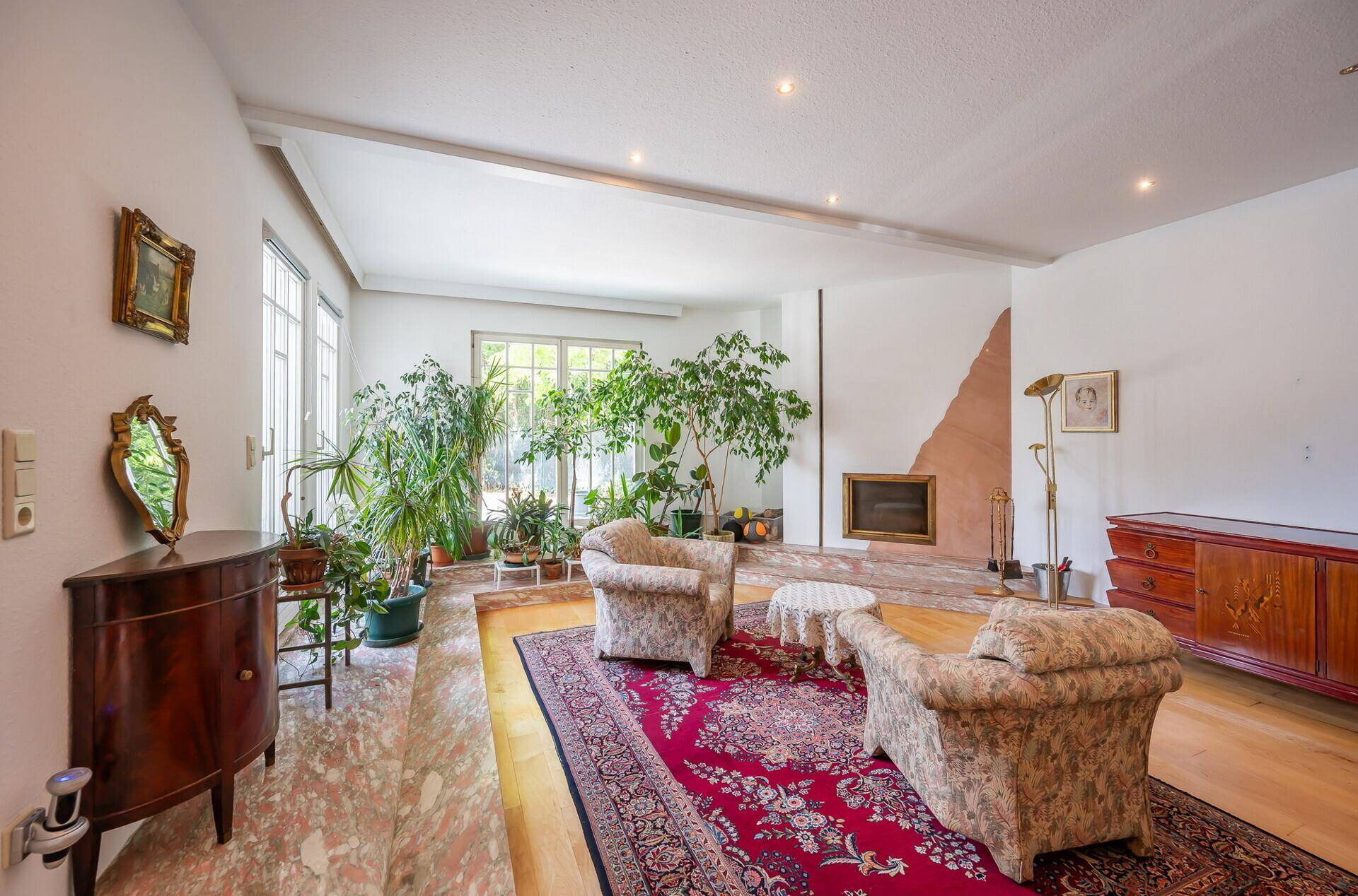 Gemütliches Wohnzimmer mit Kamin, Parkettboden und Blick auf den Garten.
