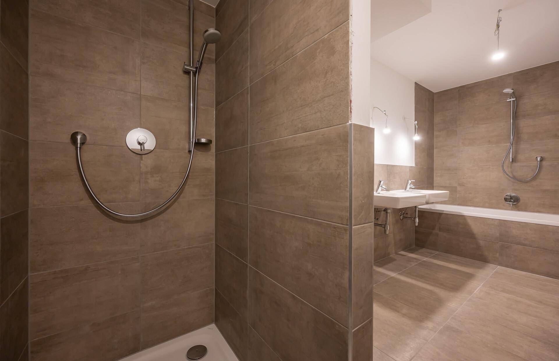 Duschbereich im modernen Badezimmer mit großen braunen Fliesen und integrierter Duscharmatur.