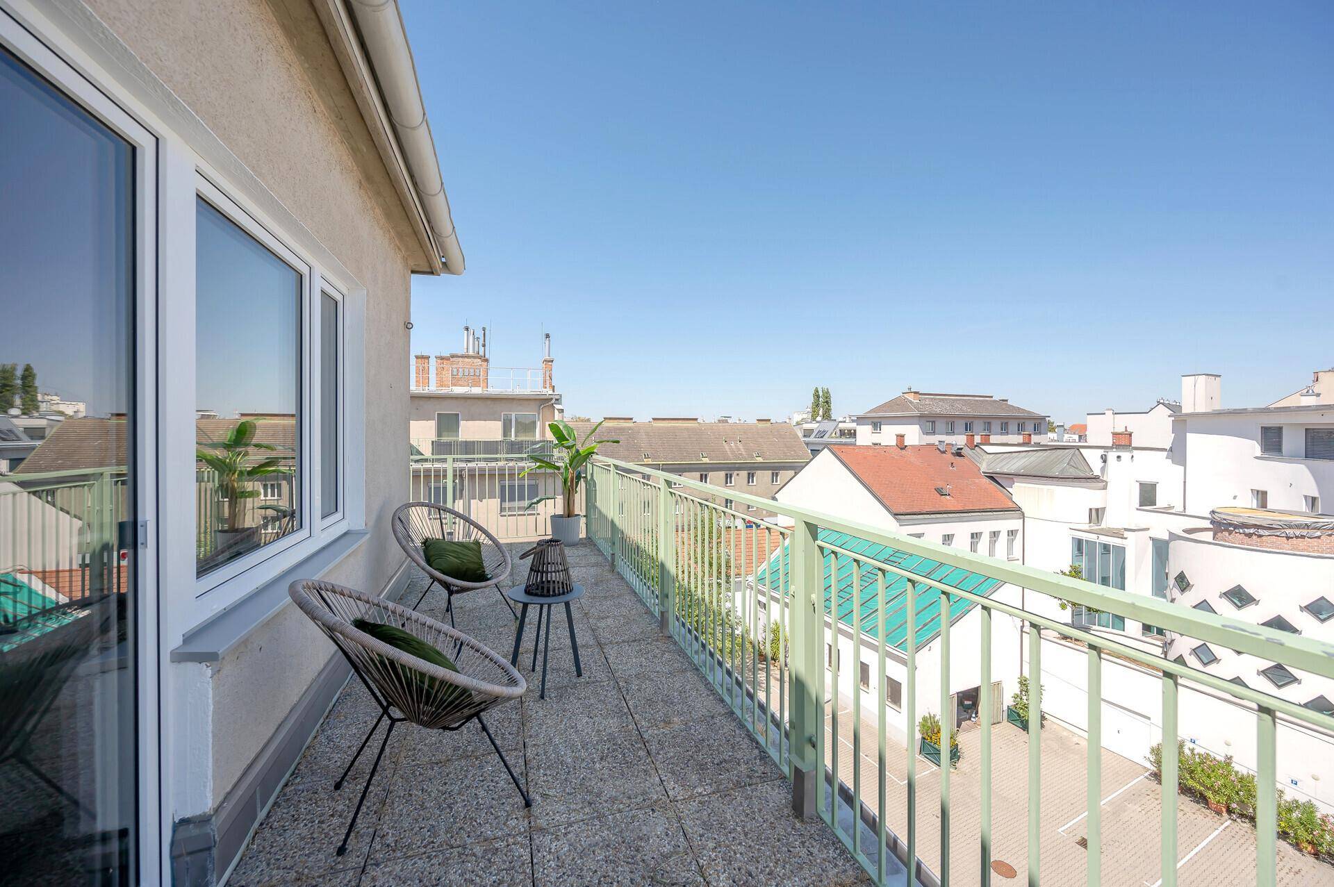 Geräumiger Balkon mit Sitzgelegenheiten und weitem Blick über die Stadt.
