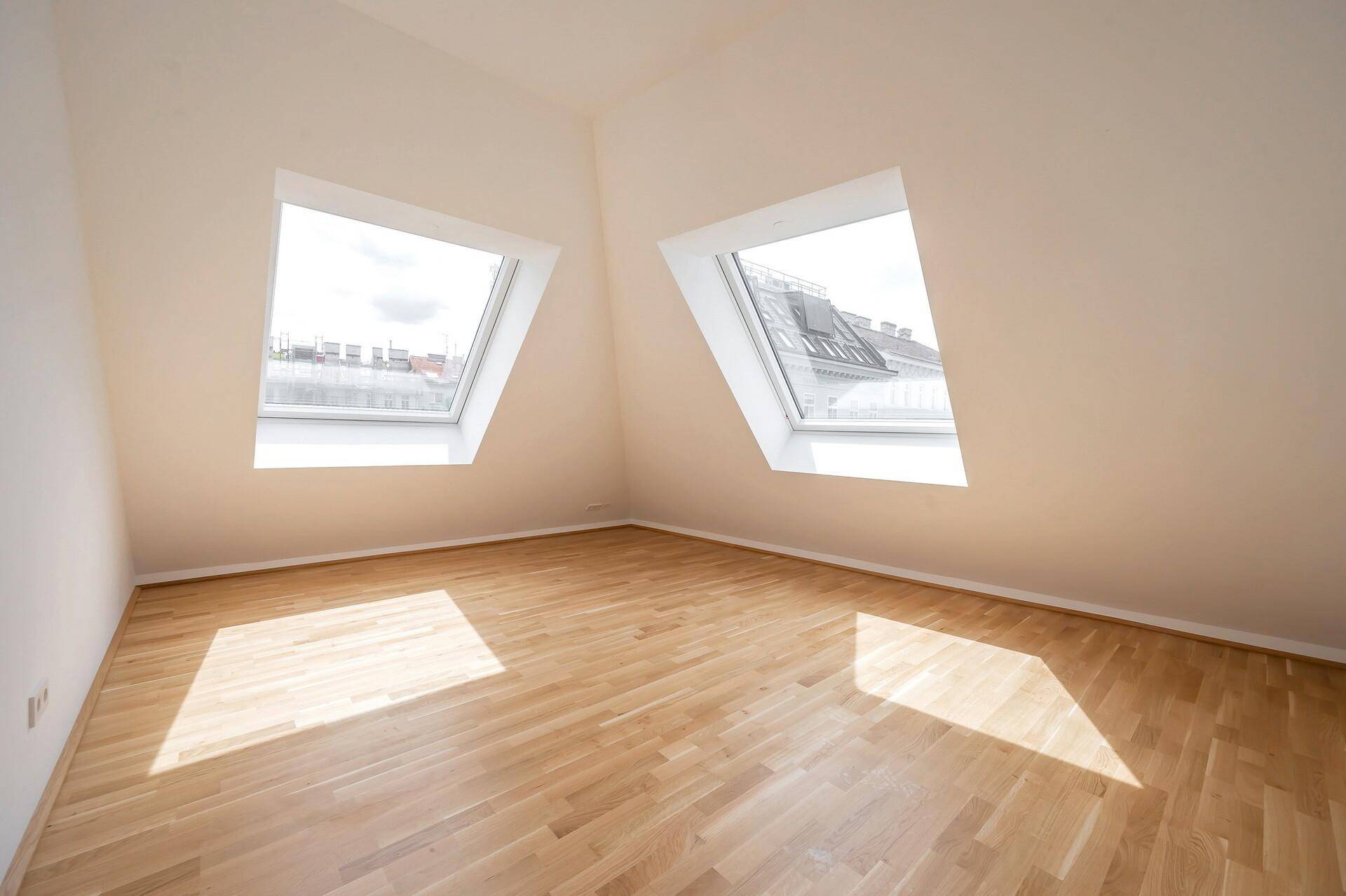 Helles Zimmer mit Holzparkett und zwei großen Dachfenstern, ideal als Schlaf- oder Arbeitszimmer.