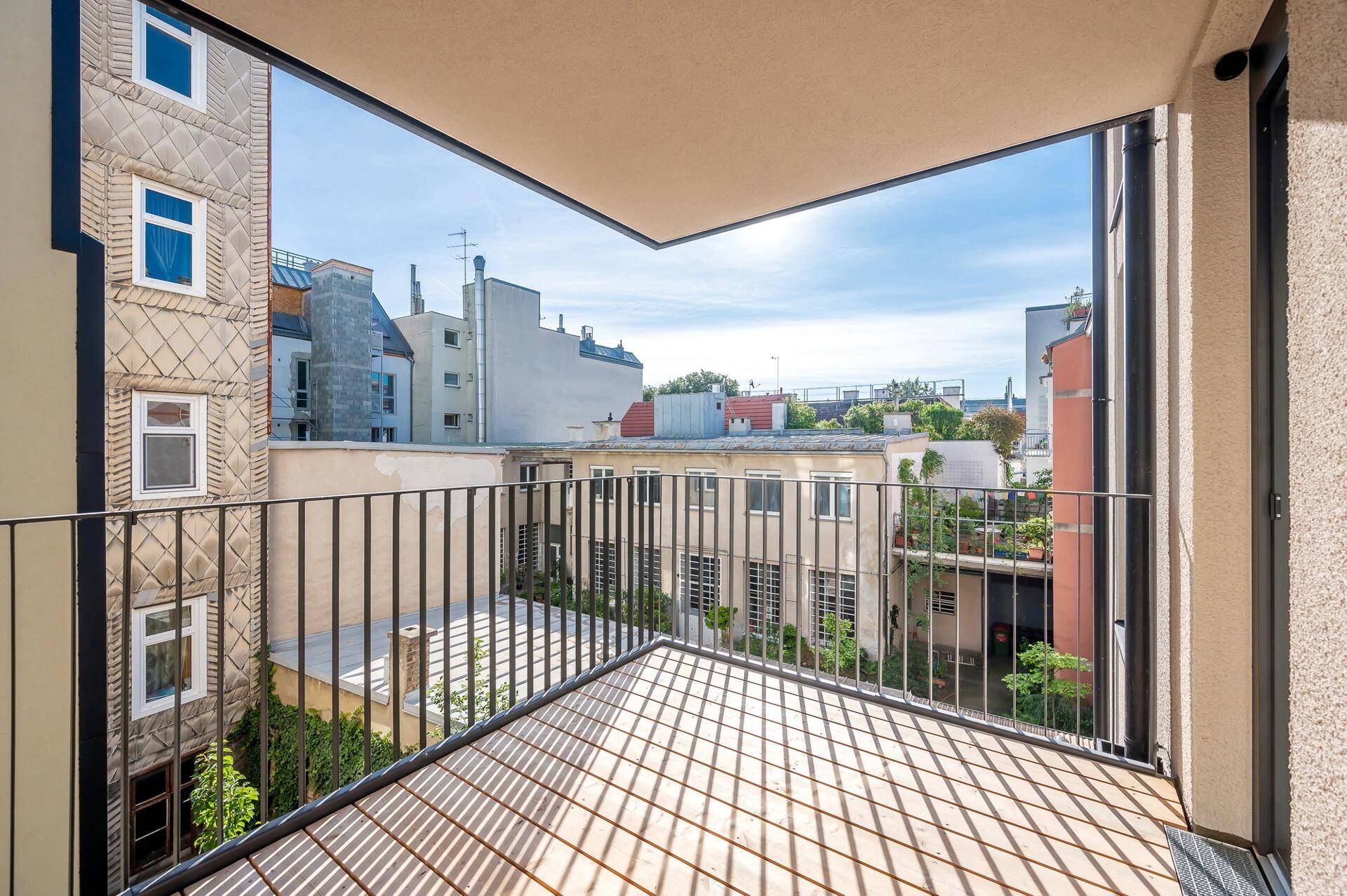 Balkon mit Blick auf die Stadt, umgeben von anderen Wohngebäuden unter blauem Himmel.